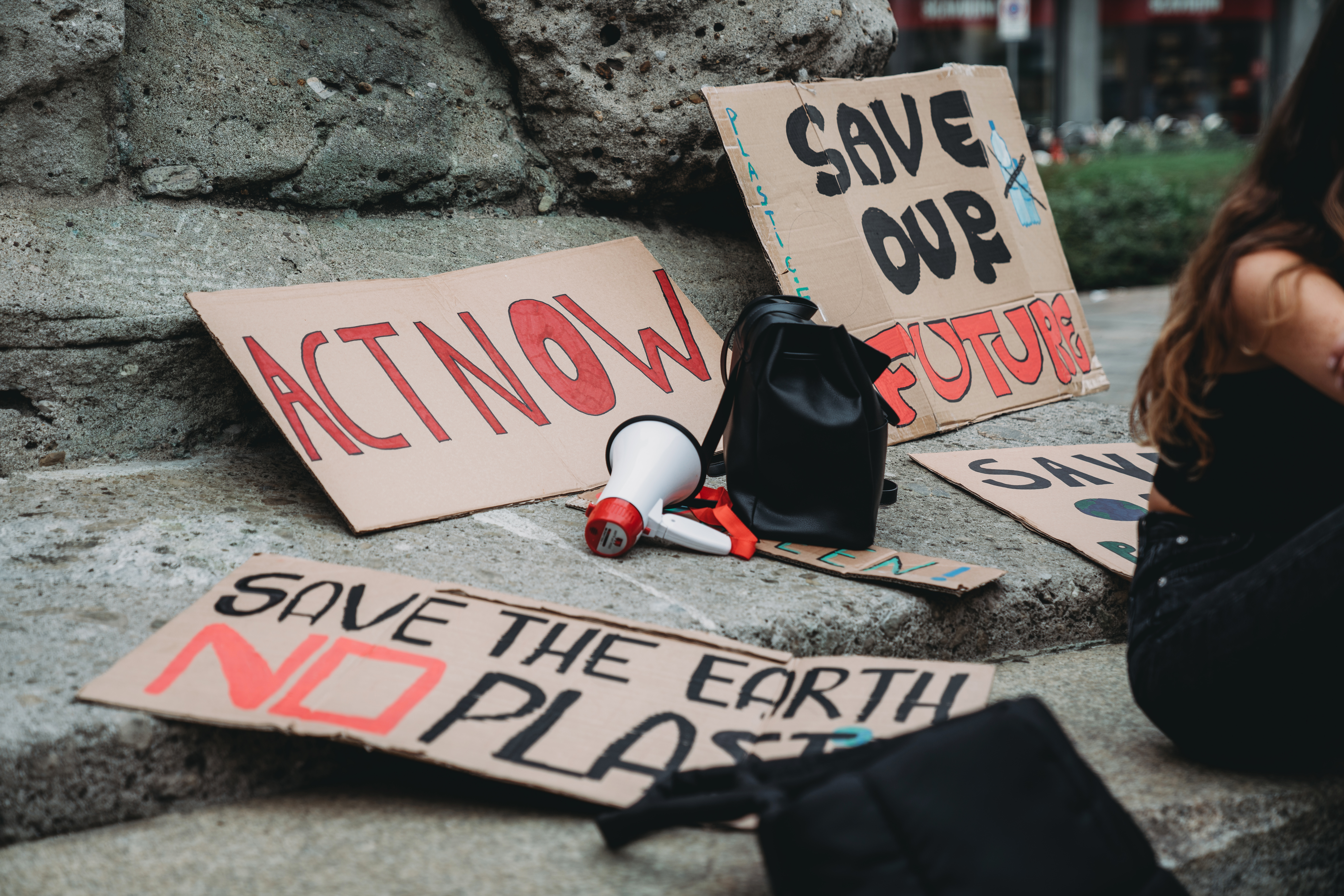 Climate protest signs “Act now” and “save our future” lying on the ground beside a megaphone.