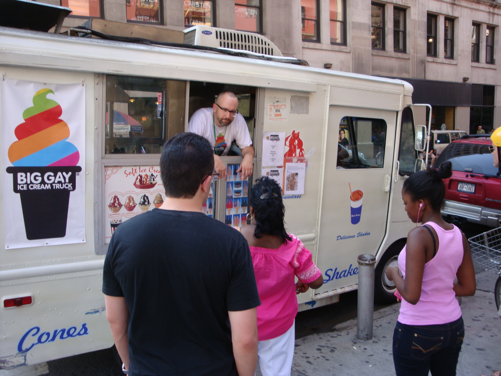 A man, Doug Quint, hangs out the window of a soft serve truck with the branding Big Gay Ice Cream.