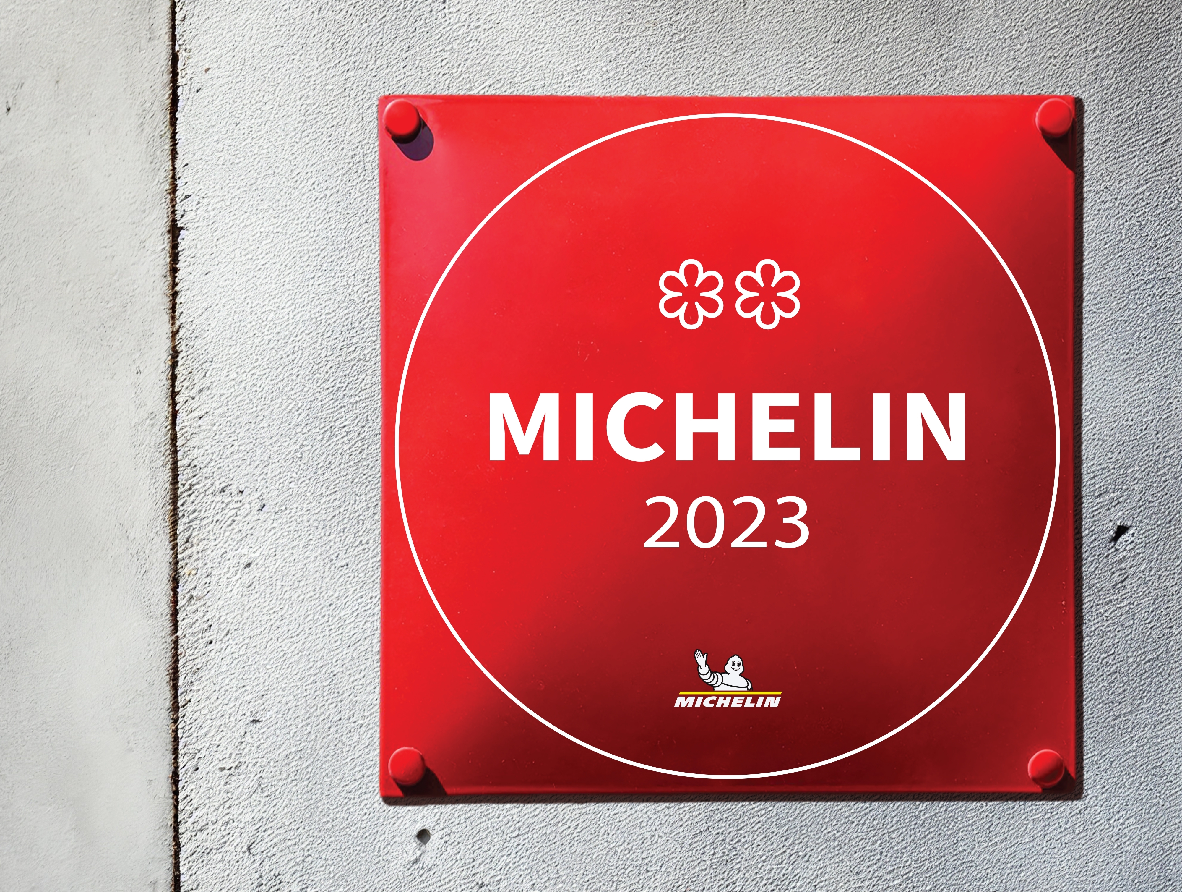 A red plaque posted outside of a restaurant displaying its Michelin ranking of two stars in 2023.