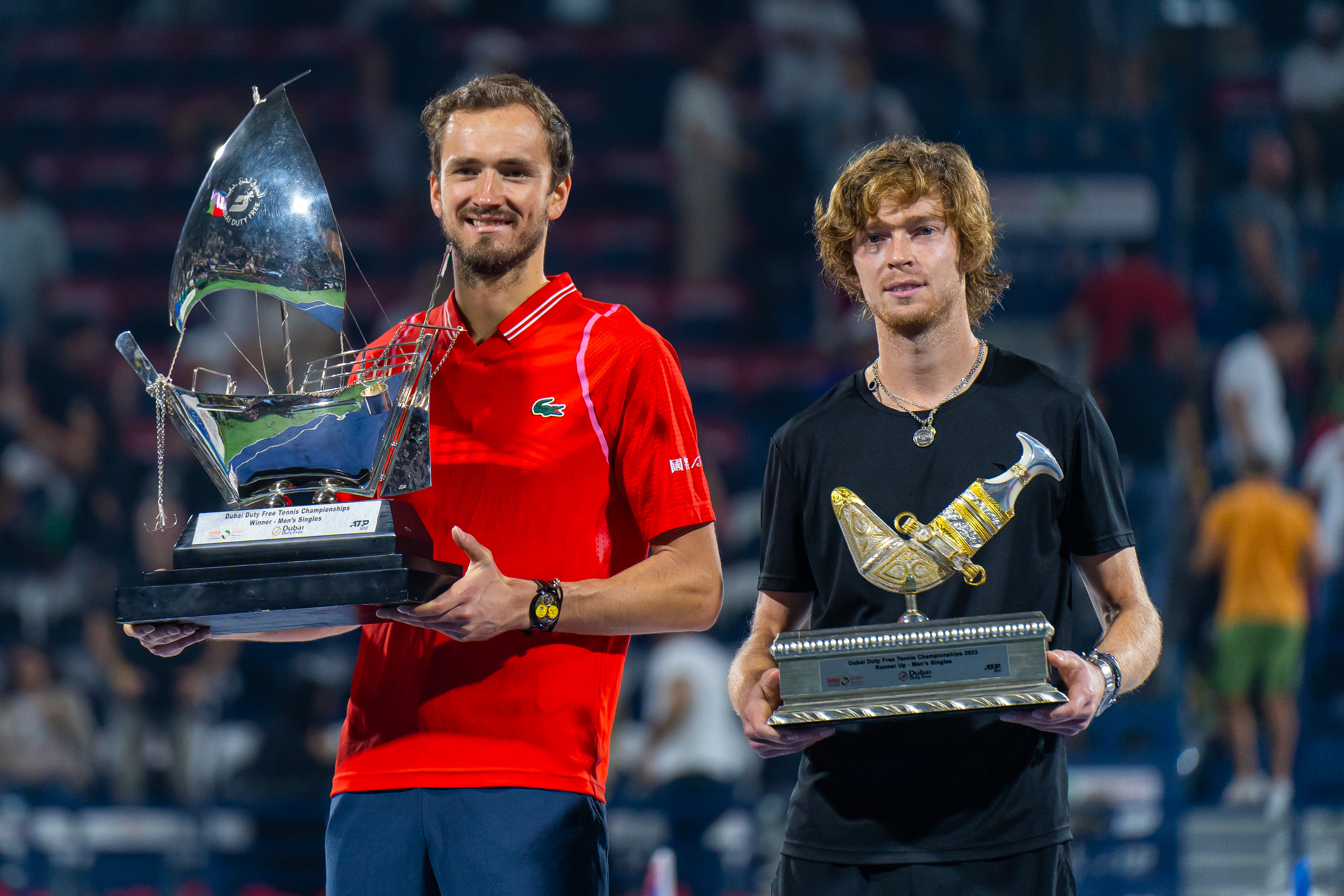 Daniil Medvedev (L) poses with the trophy alongside Andrey Rublev (R) after the finals of the Dubai Duty Free tennis tournament at Dubai Tennis stadium.