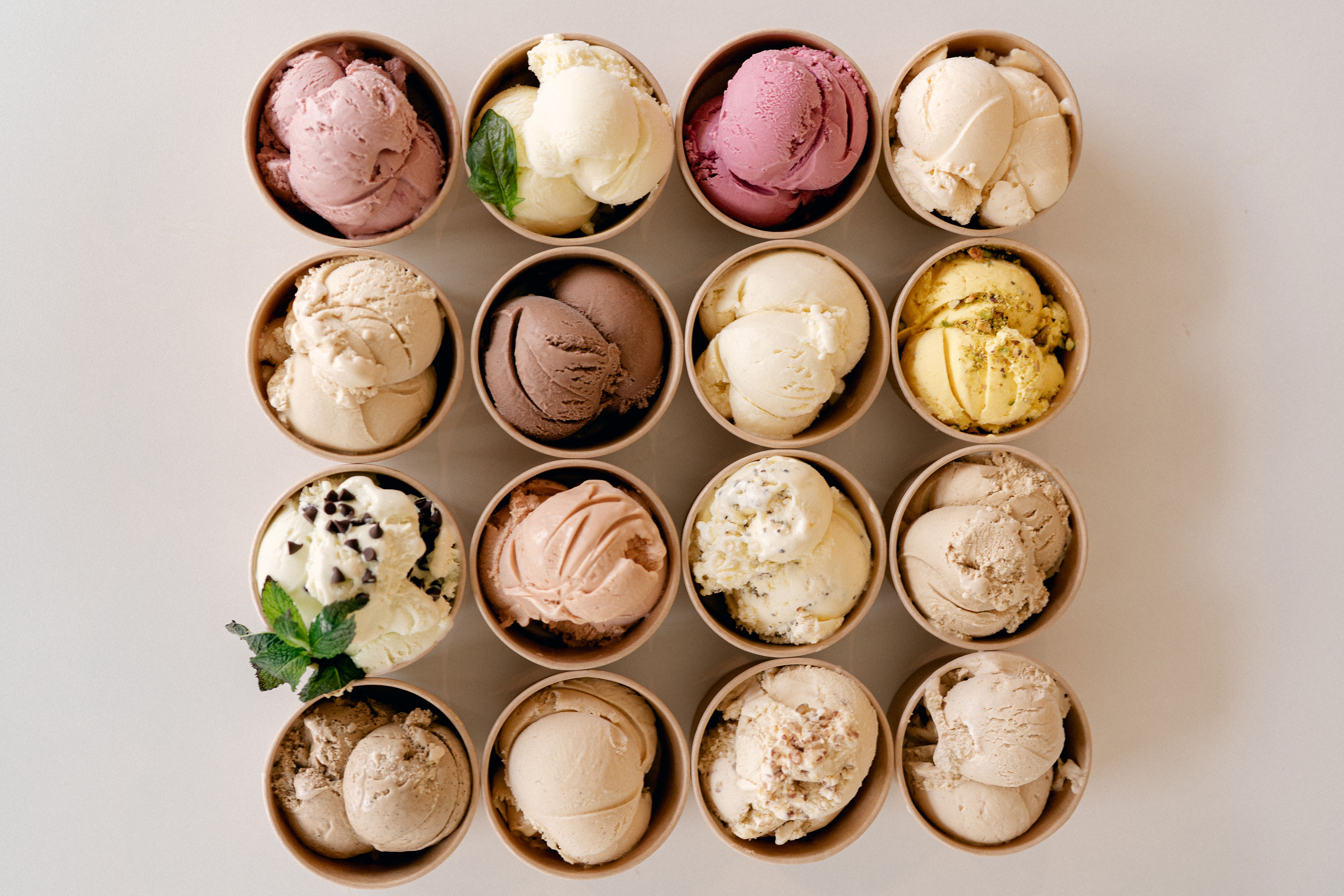 Sixteen scoops of Craft Creamery ice cream in small cardboard cups.