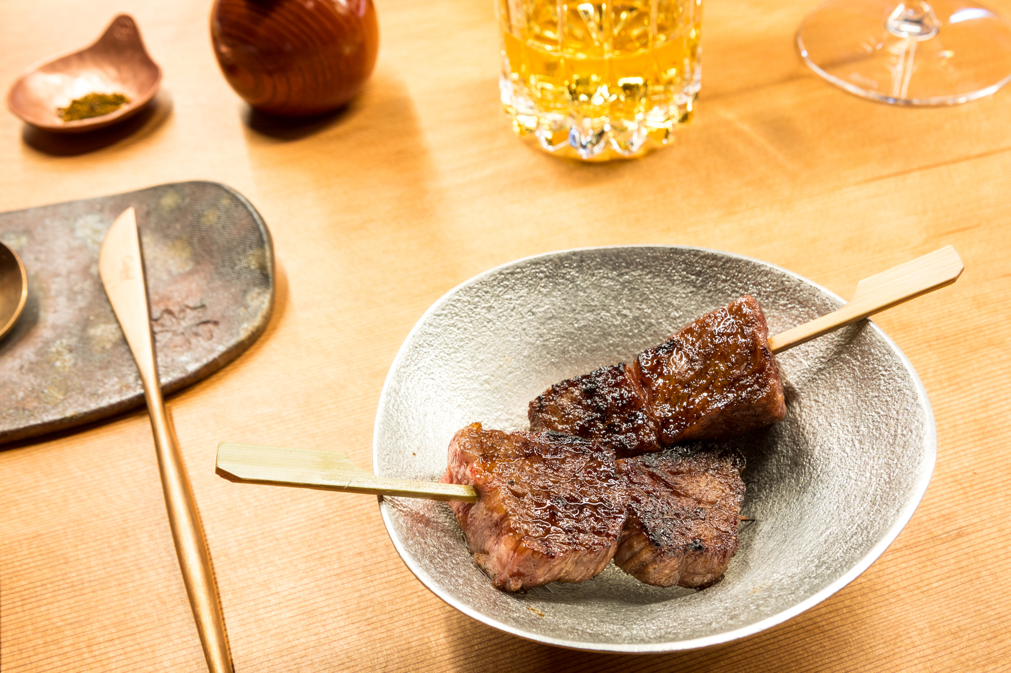 Yakitori-style skewers with cubes of wagyu steak in a shallow ceramic bowl.