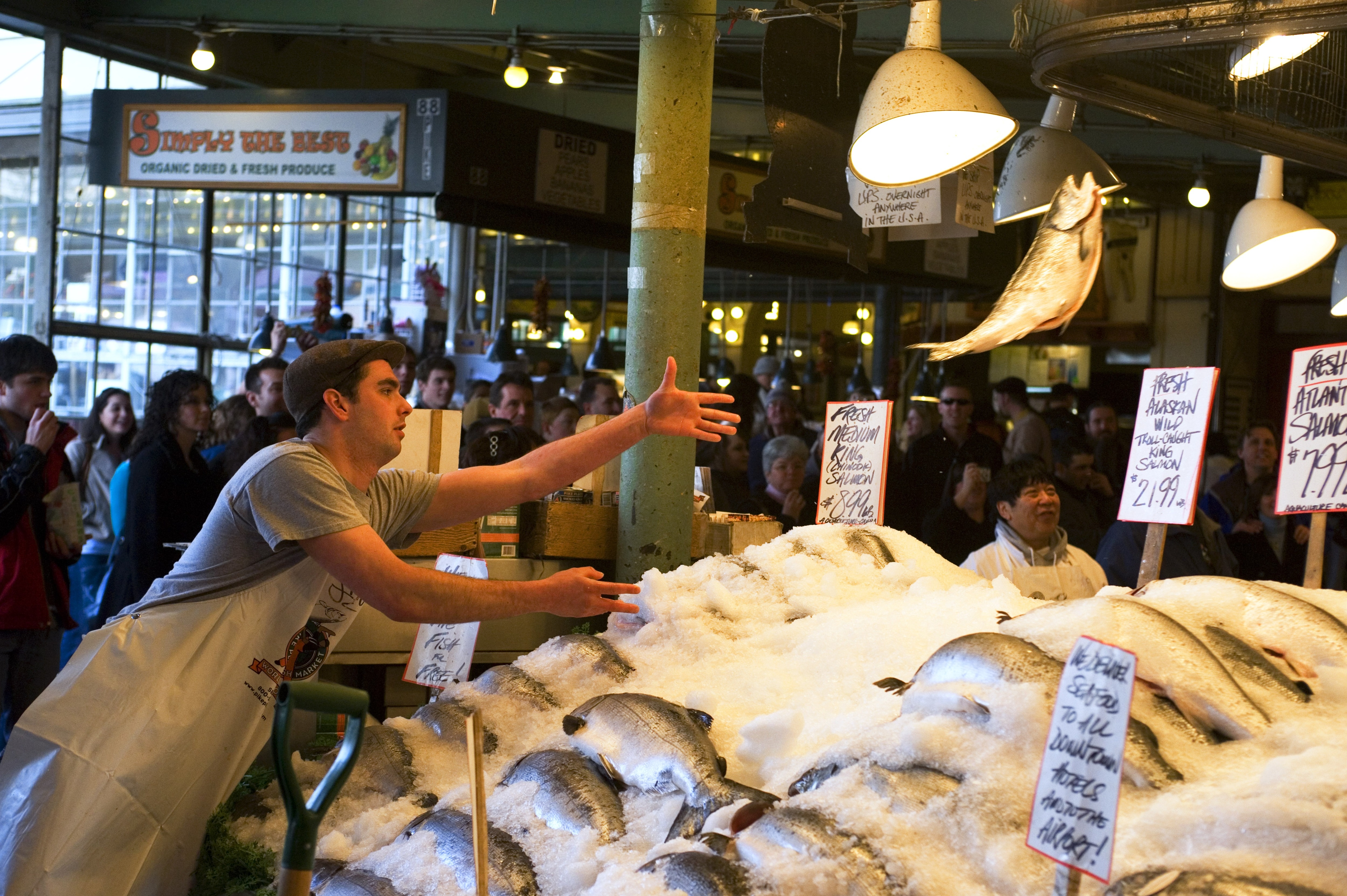 A worker at a fish market throws a fish in the air.