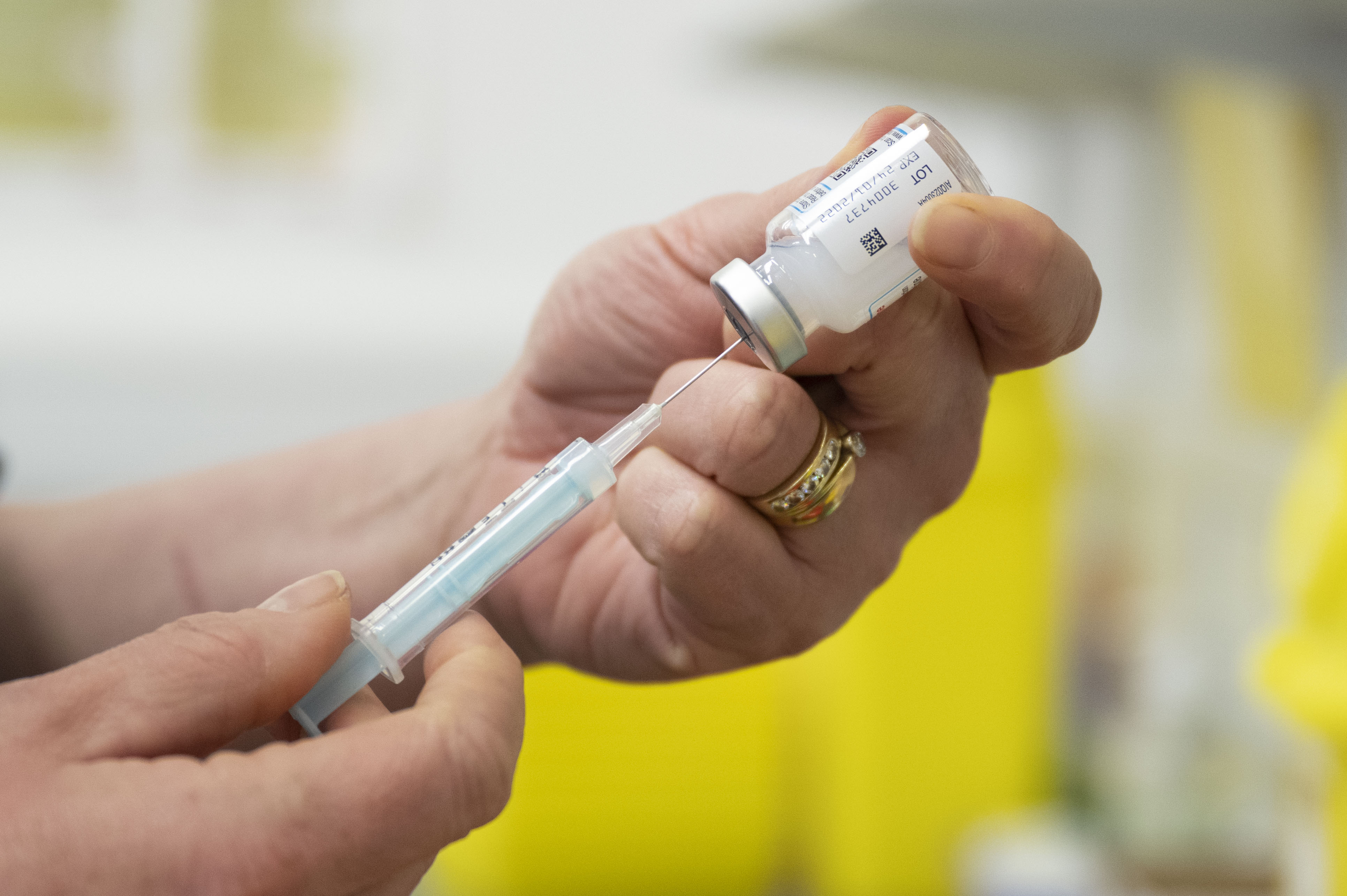 A close-up photo shows a pair of hands filling a syringe from a vial of the Moderna Covid-19 vaccine, in 2021 in Cardiff, Wales.