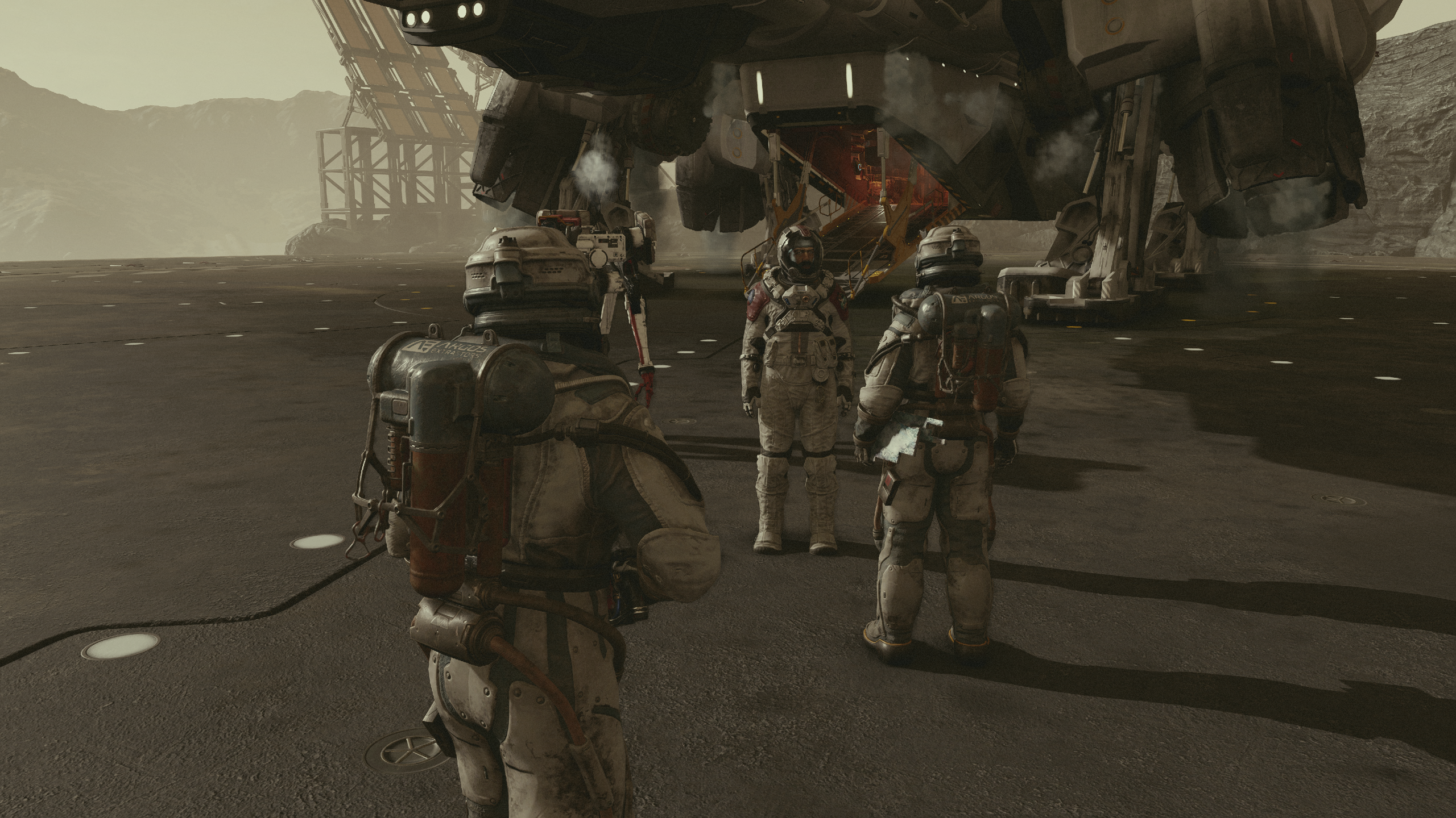 Three characters clad in spacesuits meet up in front of a spaceship at a docking bay in Starfield