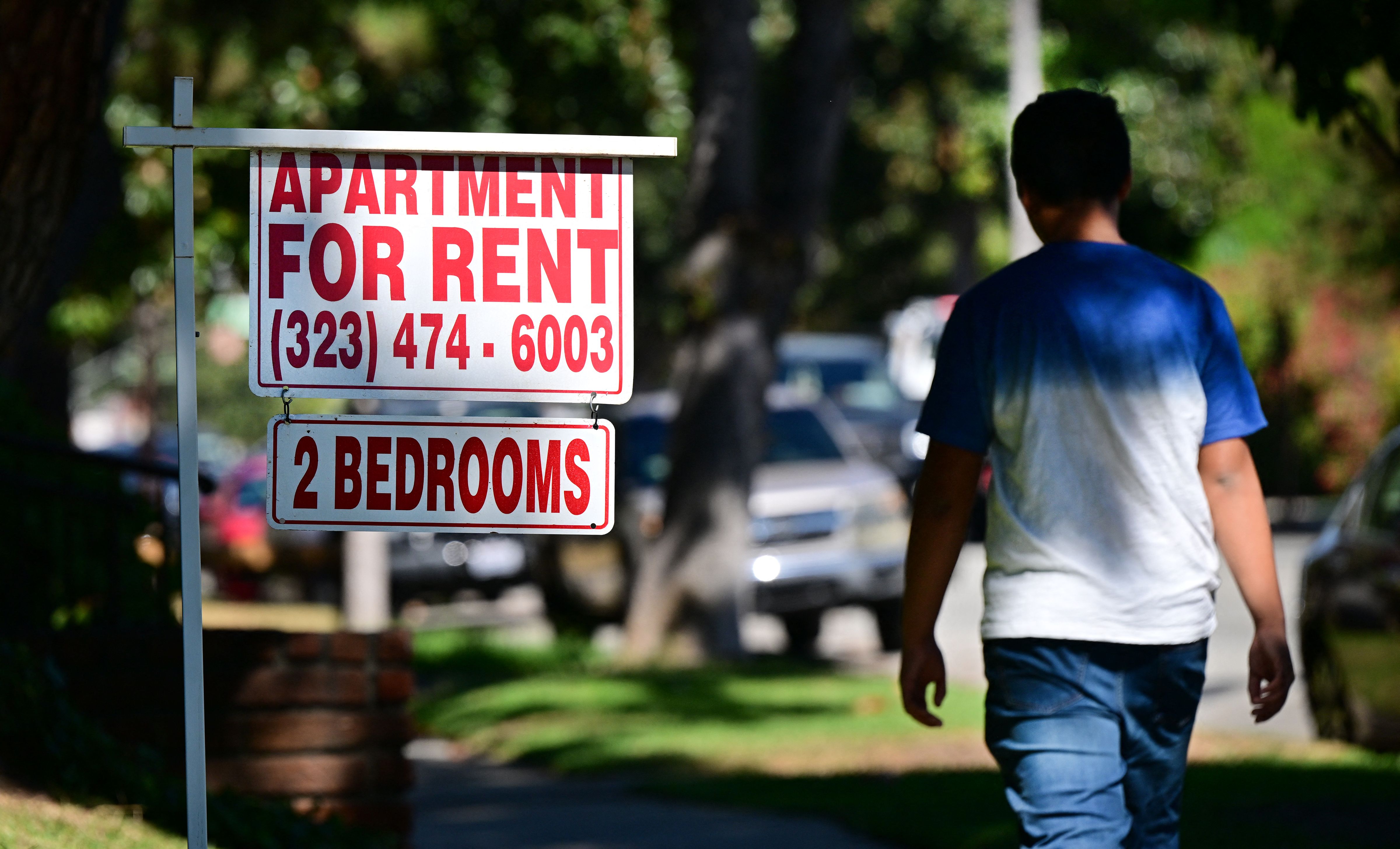 A person walks by a sign advertising a two-bedroom apartment for rent.