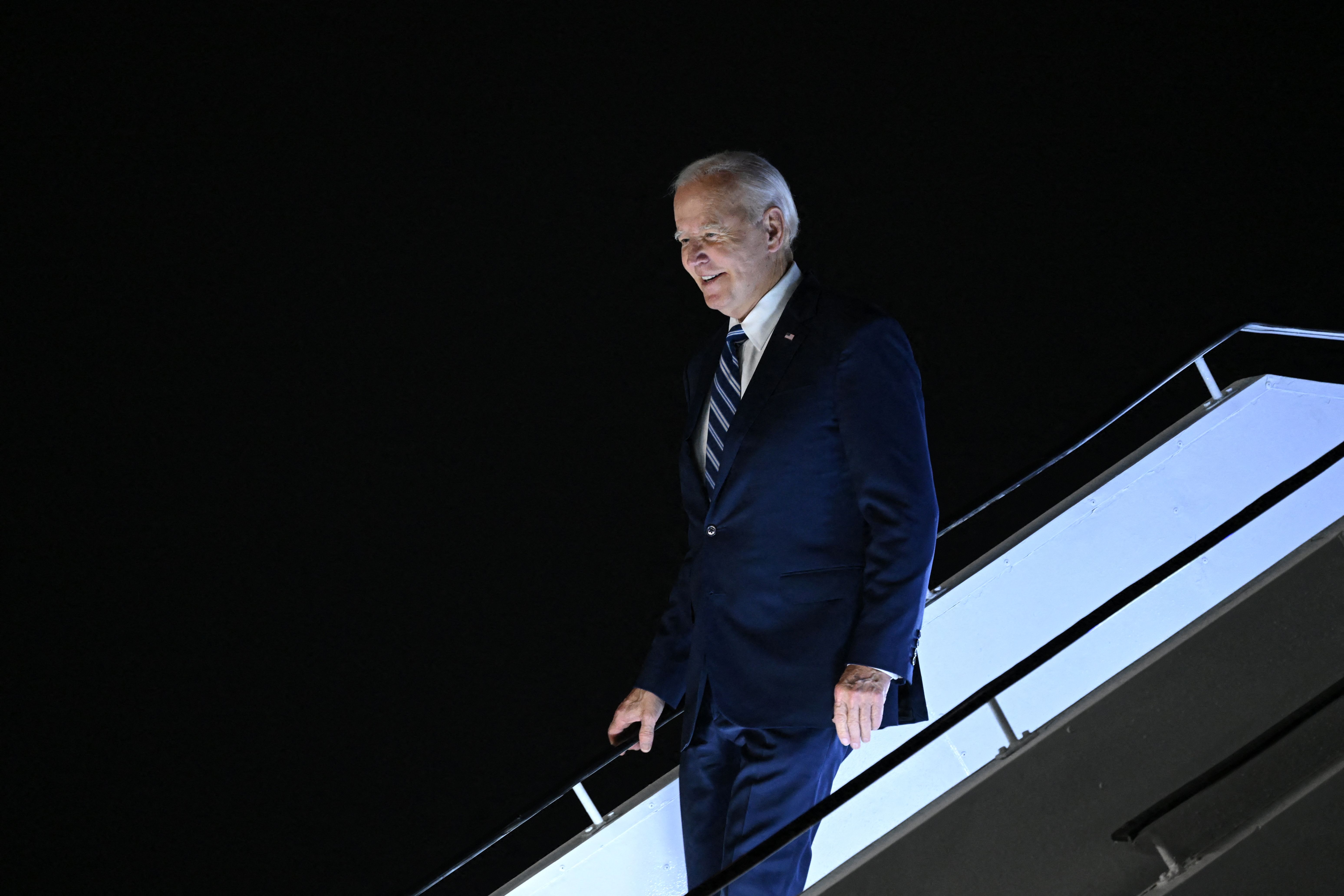 Joe Biden walking down airplane steps at night.