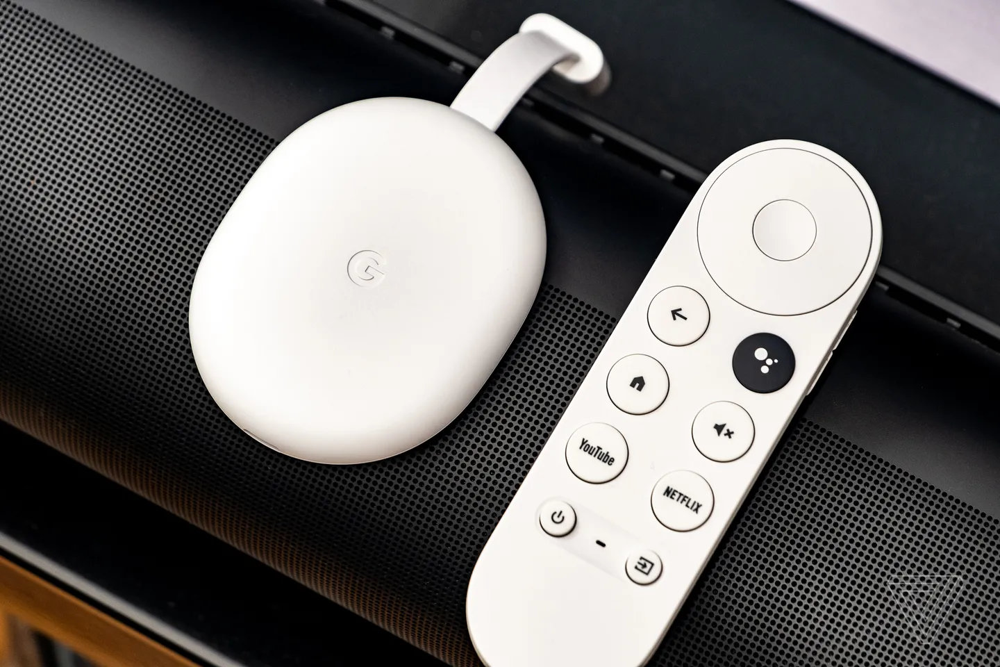 The Google Chromecast with Google TV in white, sitting on top of a soundbar.