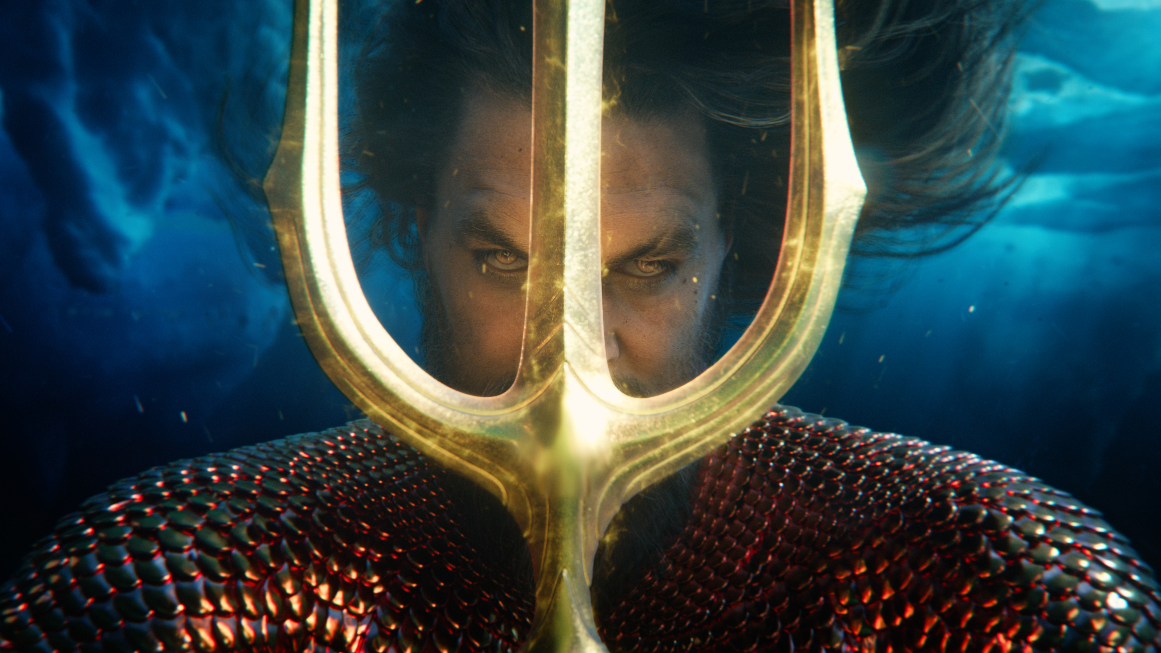 Jason Momoa’s Aquaman peers through the tines of his trident in a promo image for Aquaman and the Lost Kingdom. 