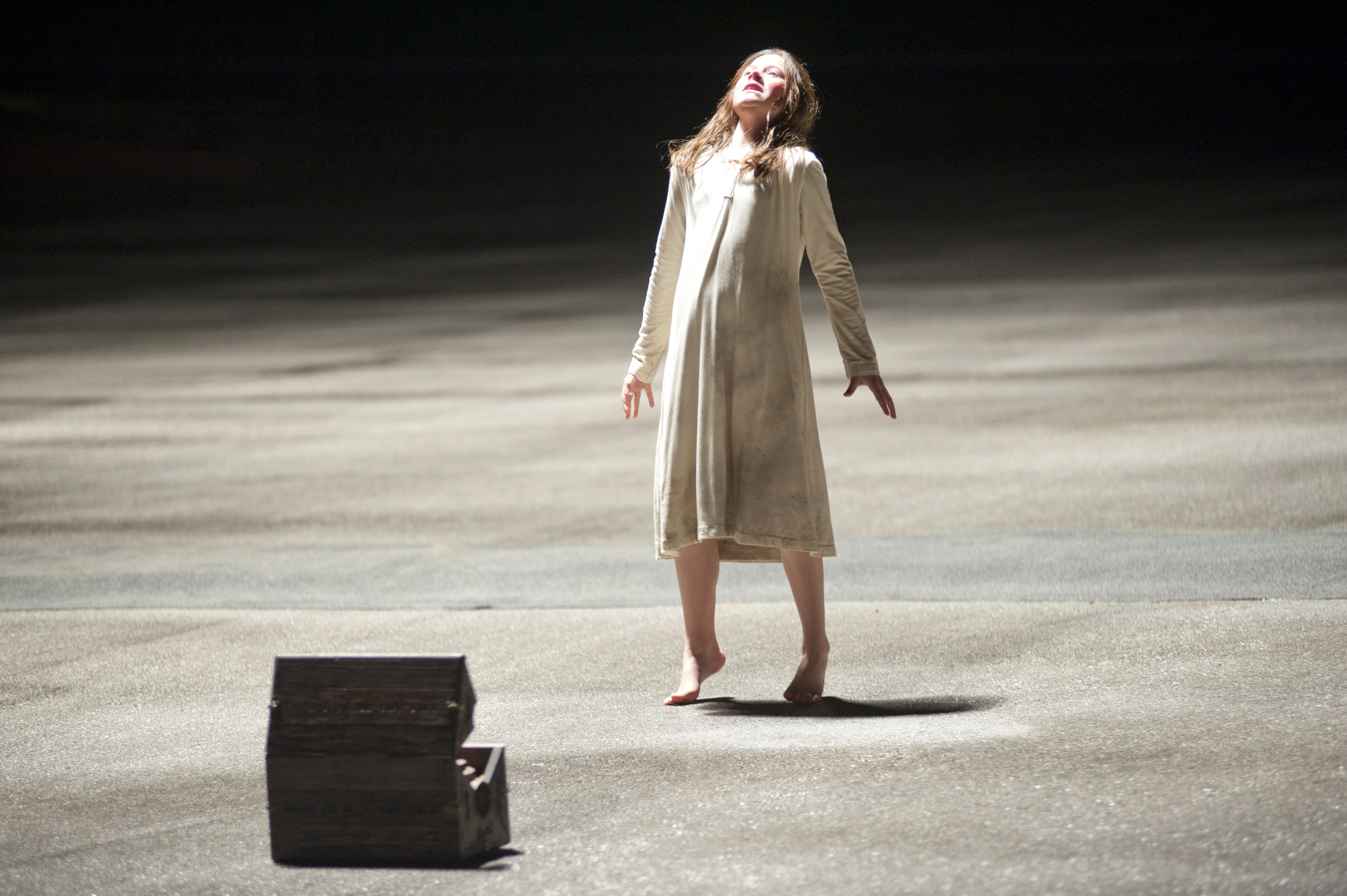 Natasha Calis as Emily in The Possession standing in an empty parking lot with a box in front of her as she is possessed by a dybbuk