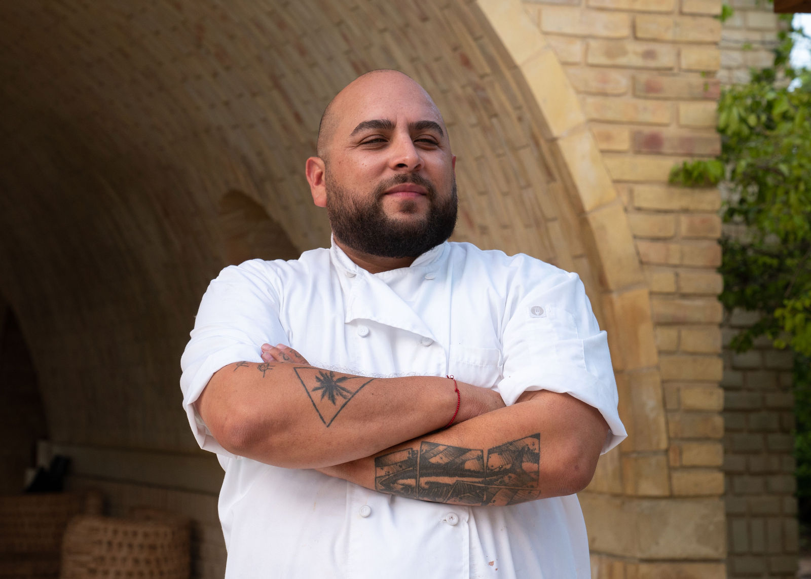 A chef stands with his arms crossed.