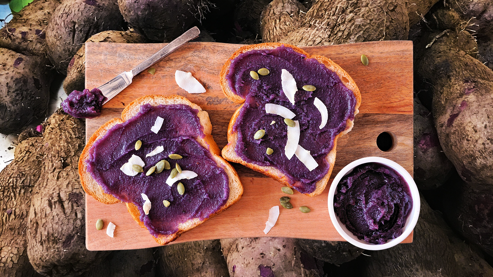 A photo of ube toast on a cutting board, behind it there is a background of zoomed in whole ube 