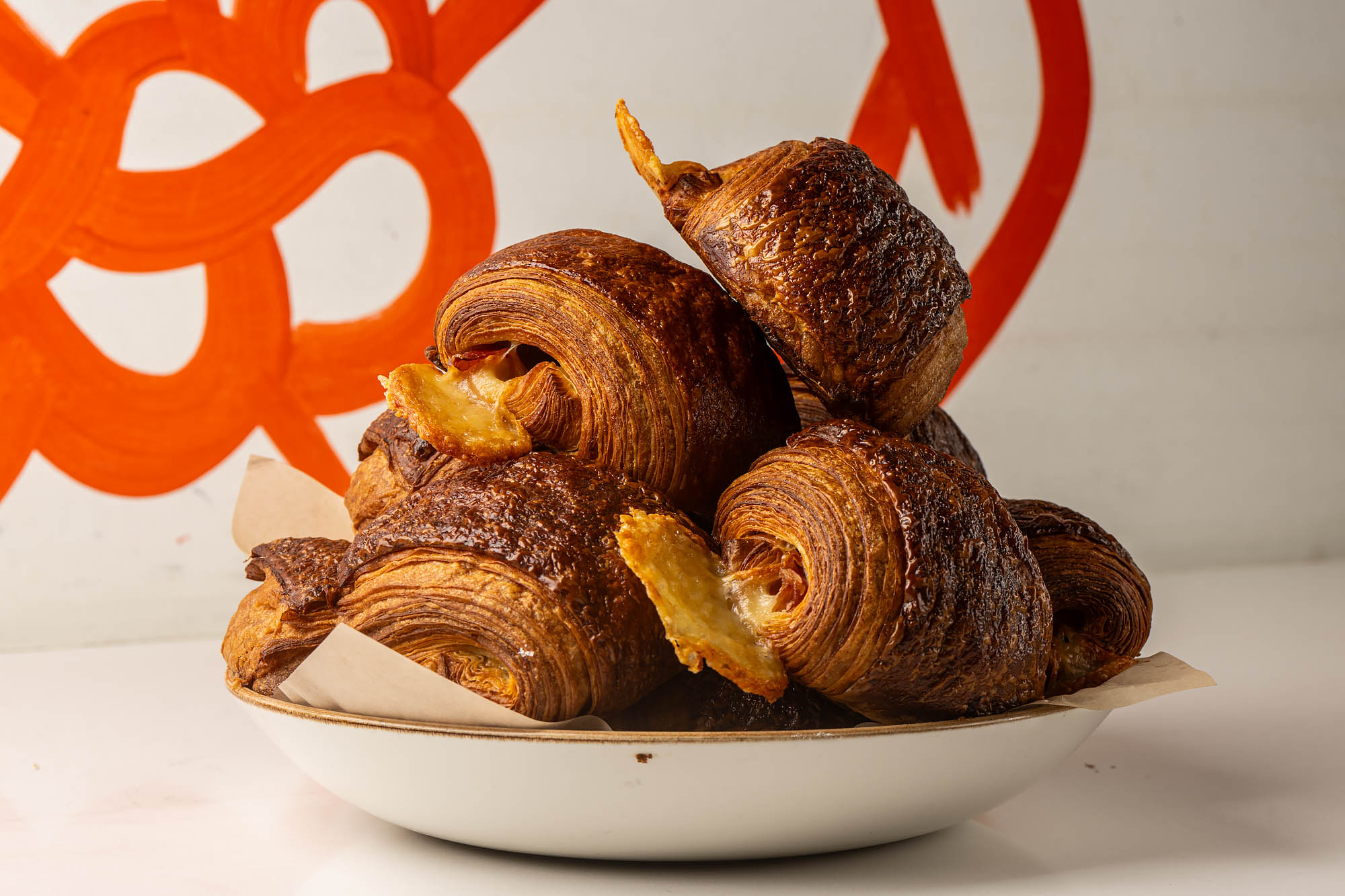 A wide bowl of croissants with layers shown at sides, plus leaks of cheese.
