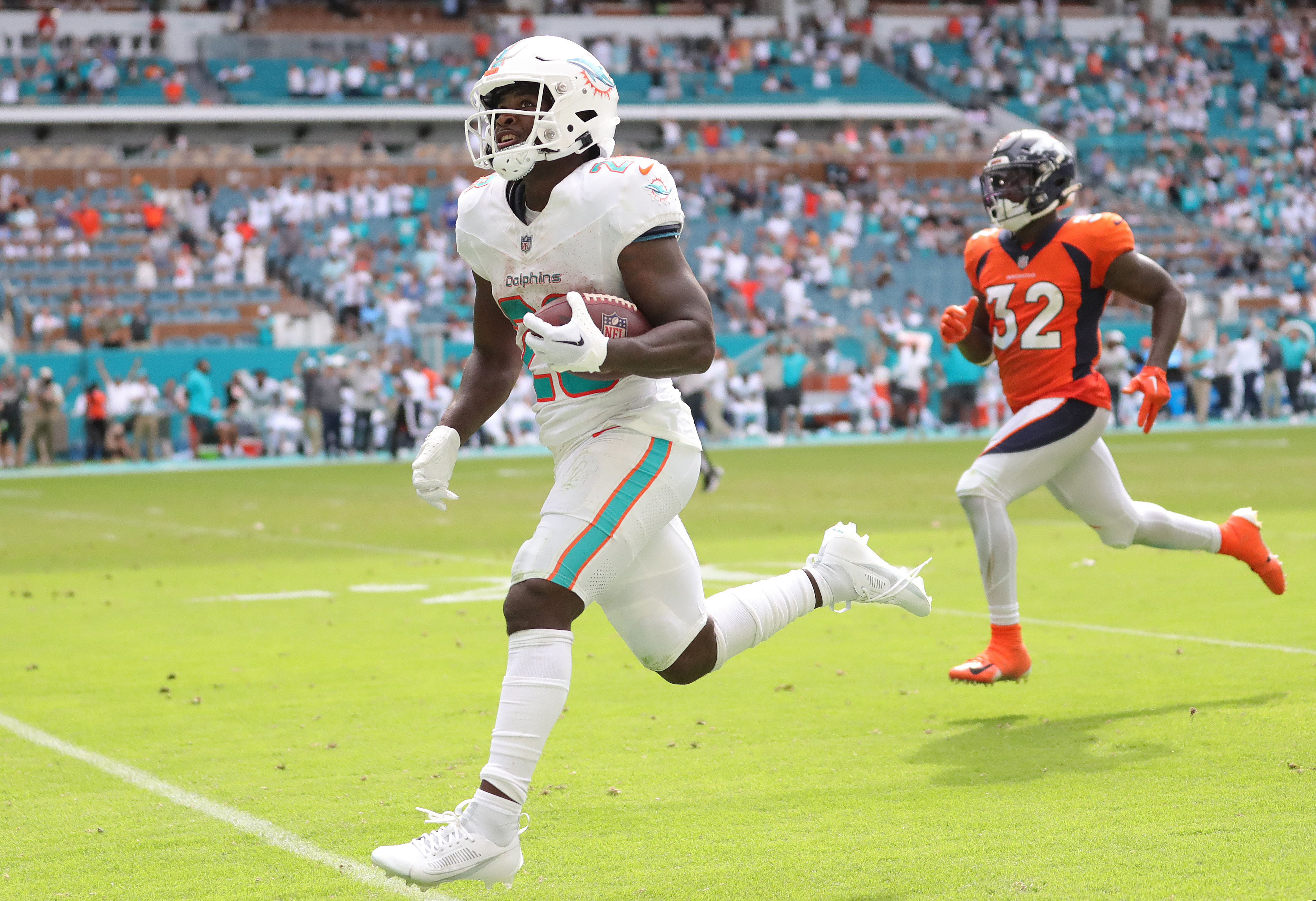 De’Von Achane #28 of the Miami Dolphins runs past Delarrin Turner-Yell #32 of the Denver Broncos while scoring a rushing touchdown during the fourth quarter at Hard Rock Stadium on September 24, 2023 in Miami Gardens, Florida.
