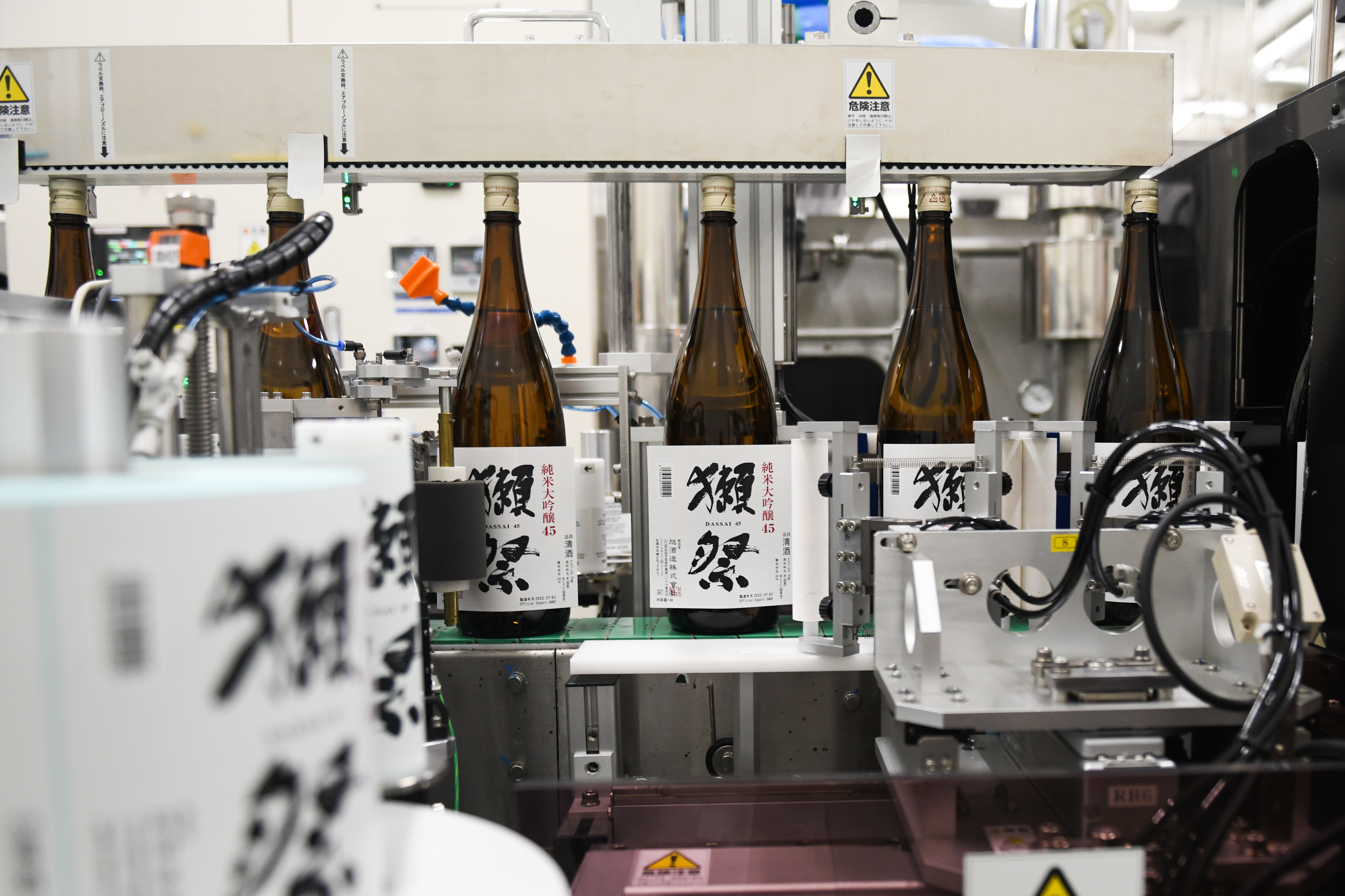 Bottles of sake from the company Asahi Shuzo are packaged on an assembly line.