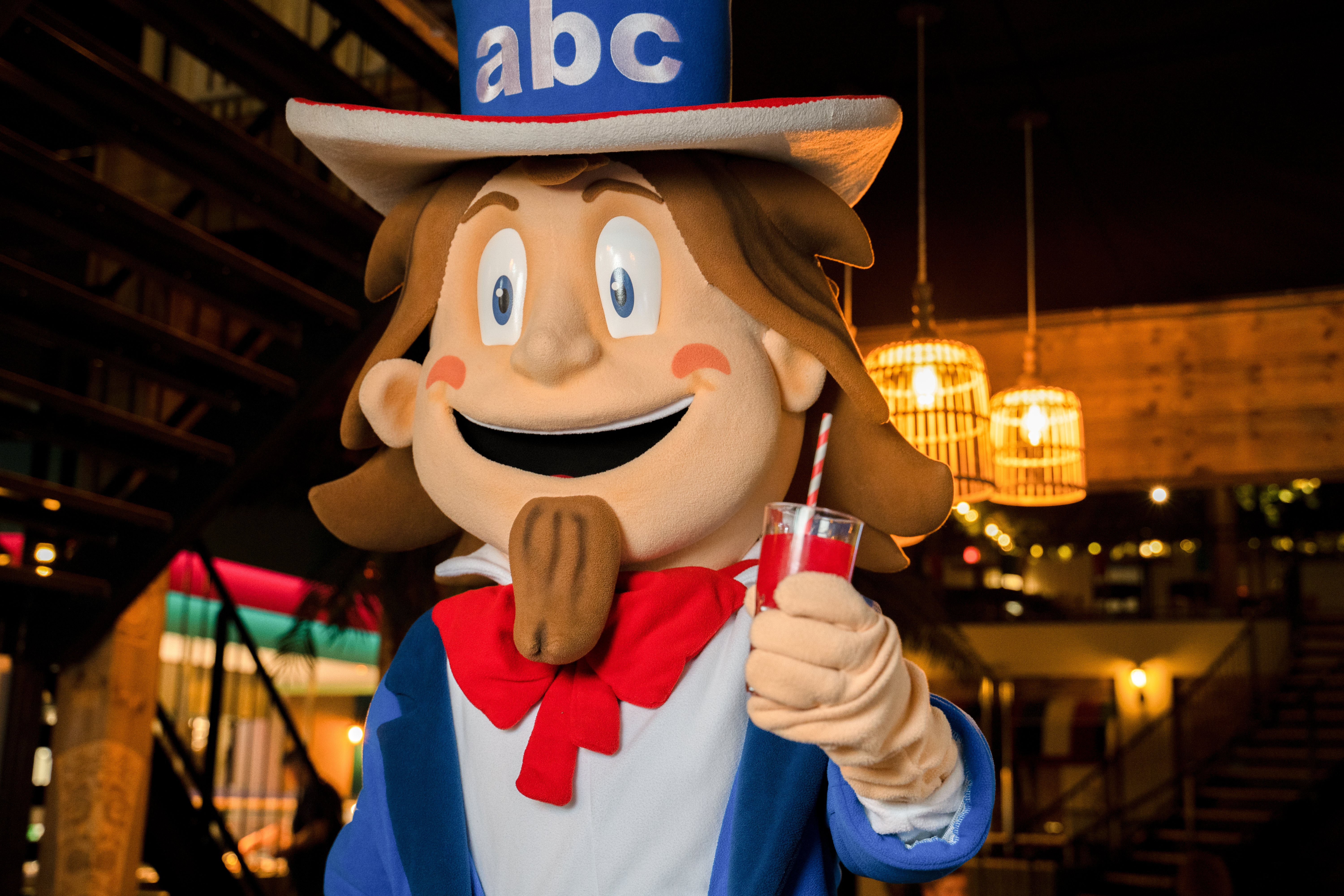 A costumed Uncle Sam holds up a red drink.
