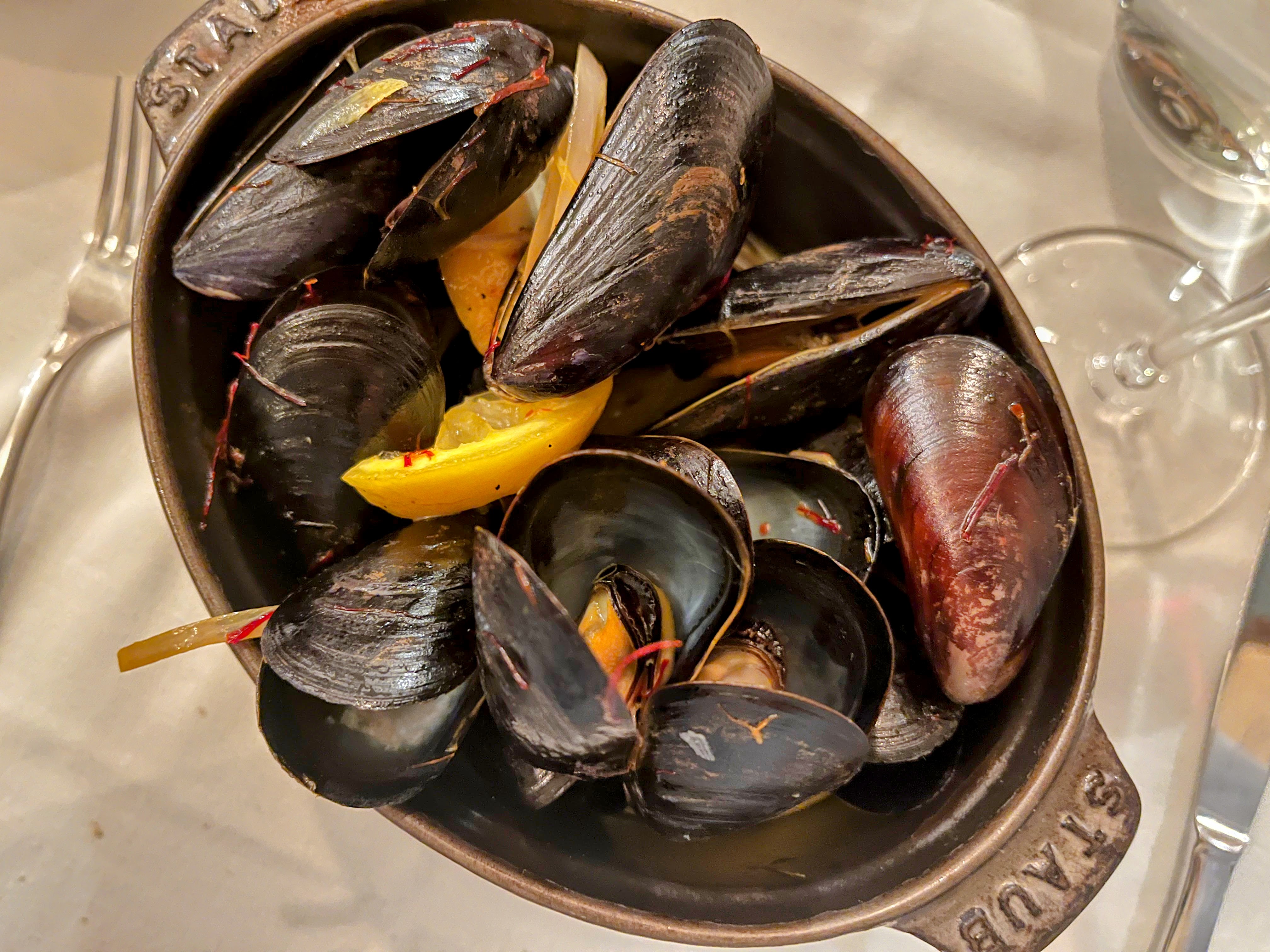 An overhead shot of a mini Staub dutch oven filled with cooked mussels.