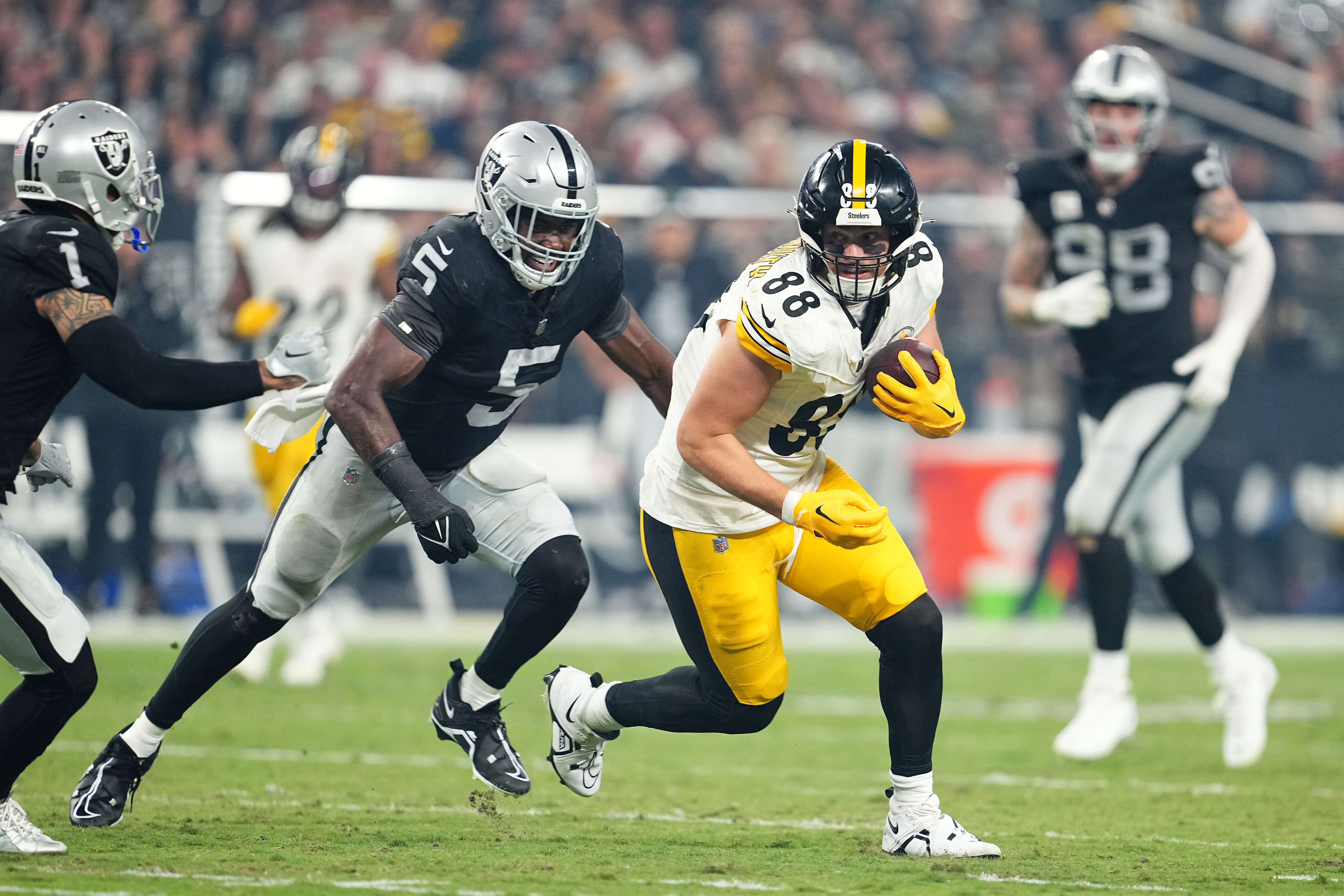 Pat Freiermuth of the Pittsburgh Steelers runs the ball after a catch while defended by Divine Deablo of the Las Vegas Raiders during the third quarter at Allegiant Stadium on September 24, 2023 in Las Vegas, Nevada.
