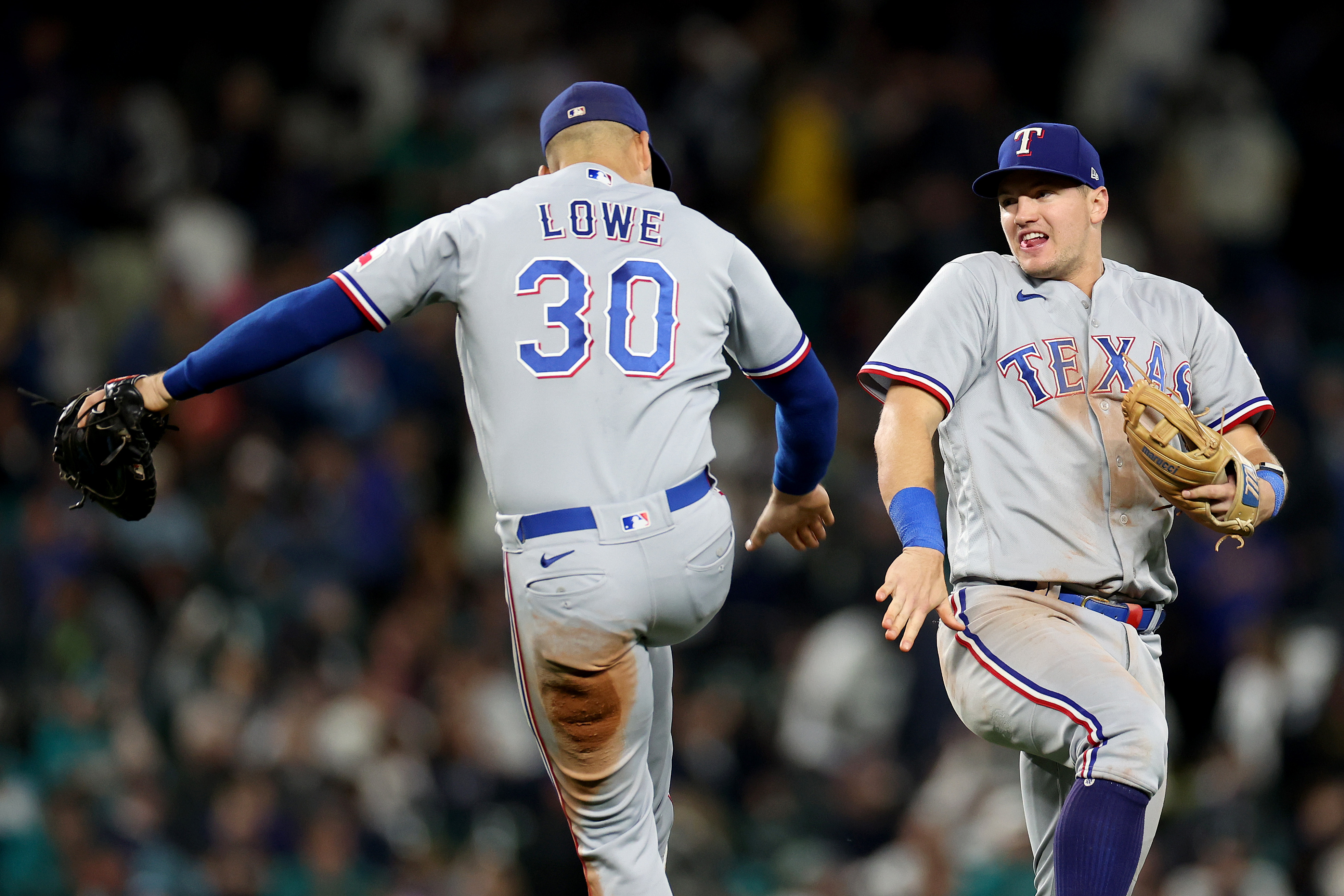 Nathaniel Lowe and Josh Jung of the Texas Rangers celebrate after beating the Seattle Mariners 6-1 to clinch a 2023 MLB playoff berth at T-Mobile Park on September 30, 2023 in Seattle, Washington.