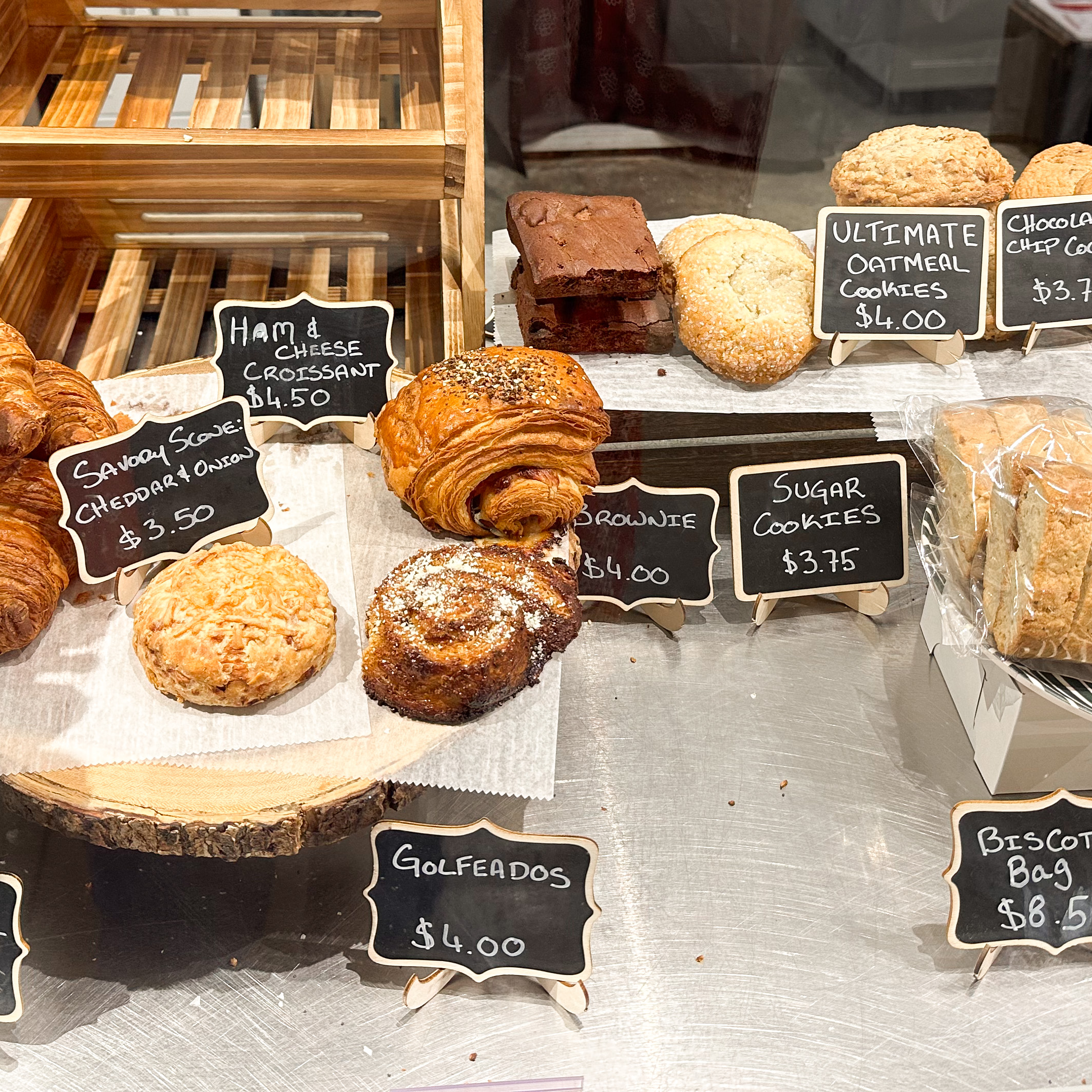 A shot of a selection of pastries on wax paper on a bakery counter. 