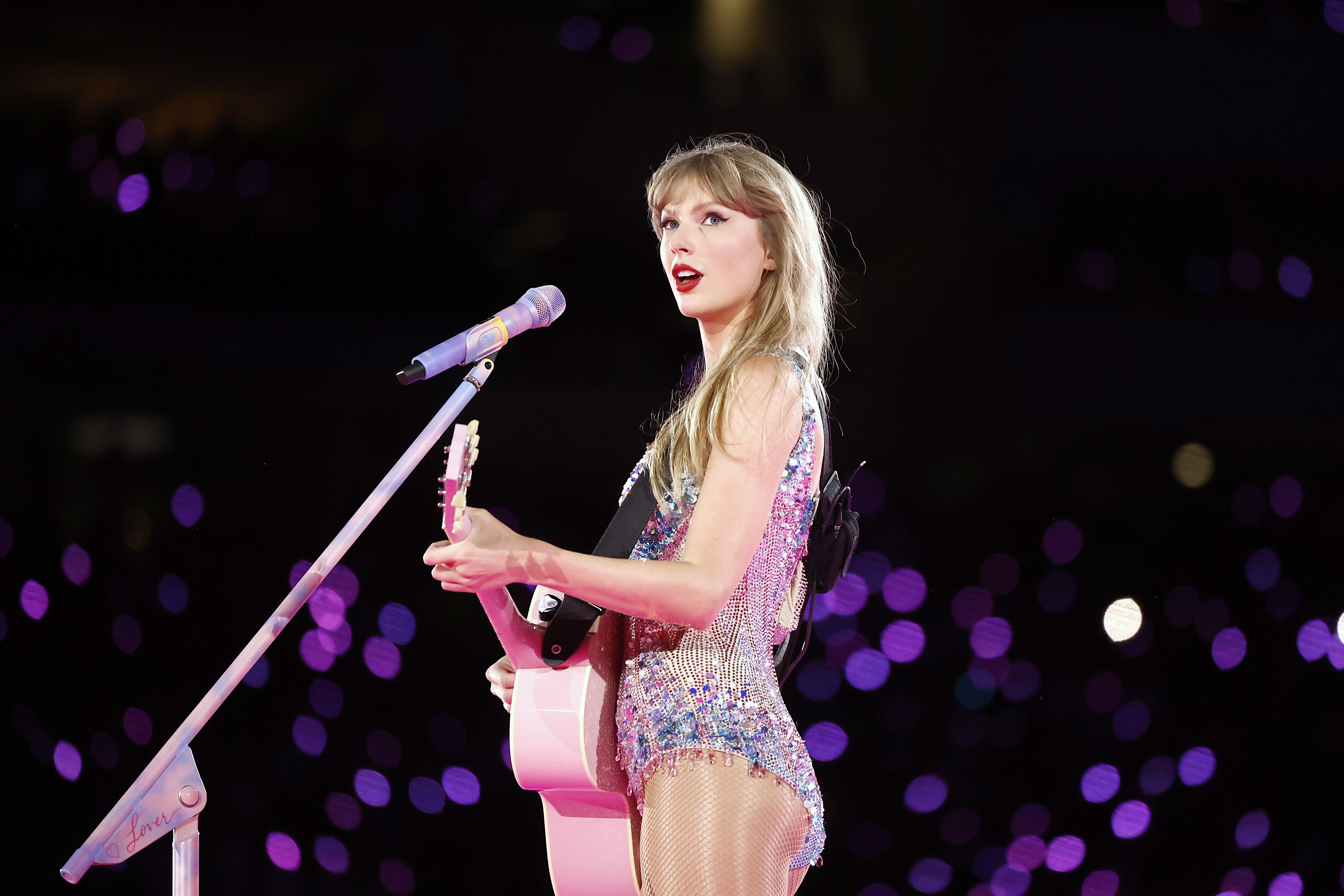 Taylor Swift holds a pink guitar and looks up to the crowd away from her mic during Taylor Swift The Eras Tour at SoFi Stadium on August 3, 2023 in Inglewood, California