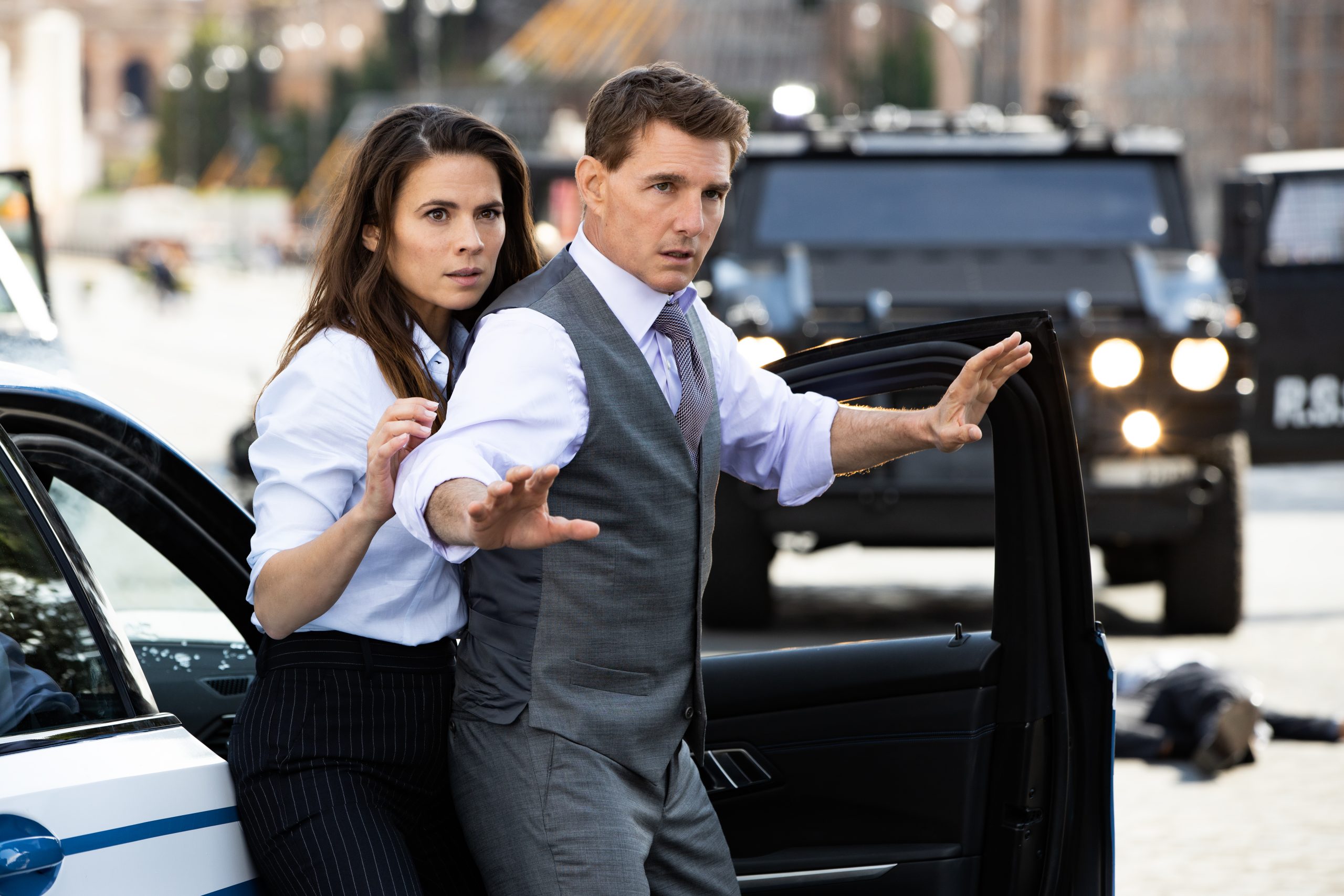 (L-R) Hayley Atwell and Tom Cruise stepping out of a car with their hands raised in Mission Impossible: Dead Reckoning Part One.