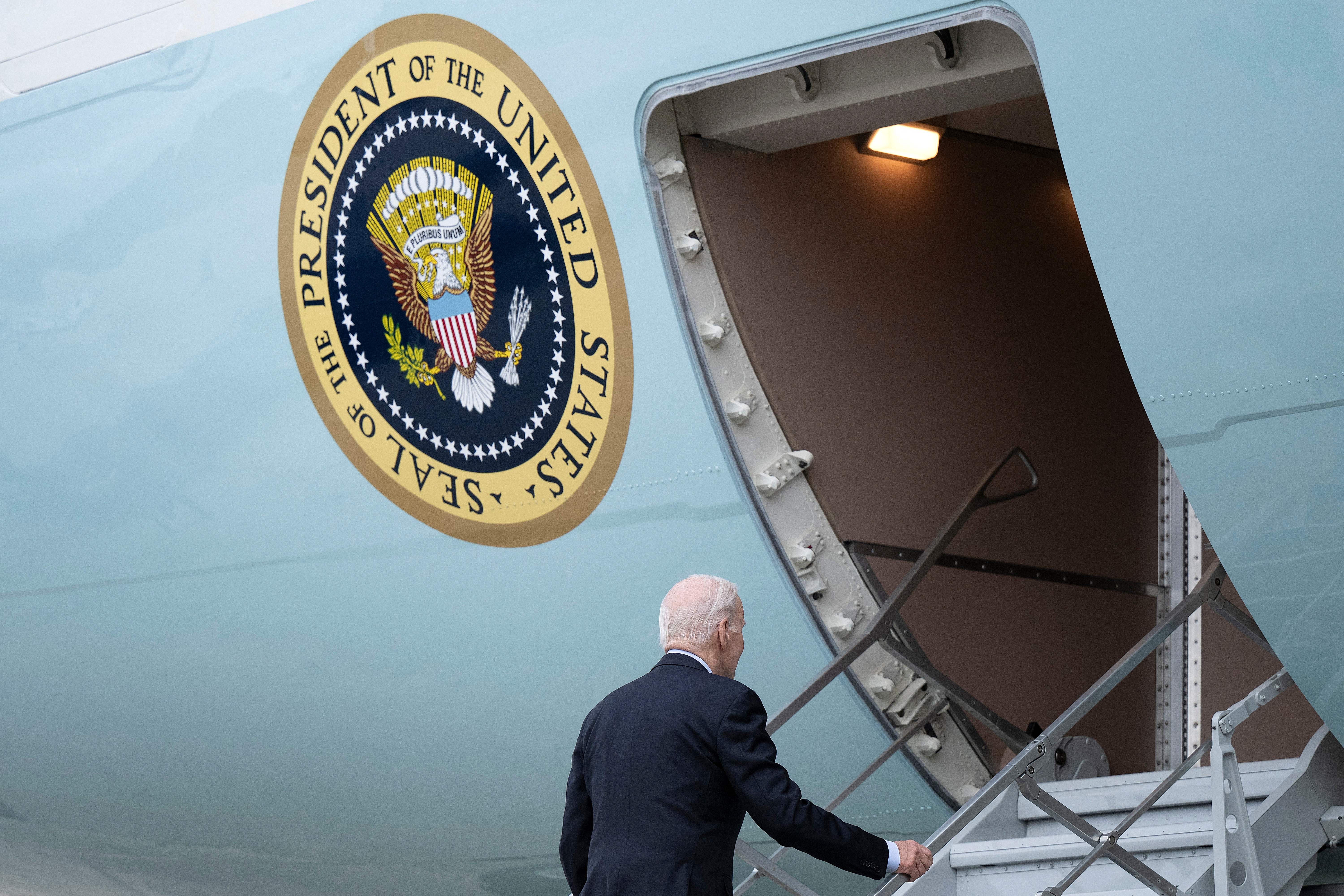 The exterior of the presidential airplane bears a large seal of the president beside its door, into which Joe Biden climbs.