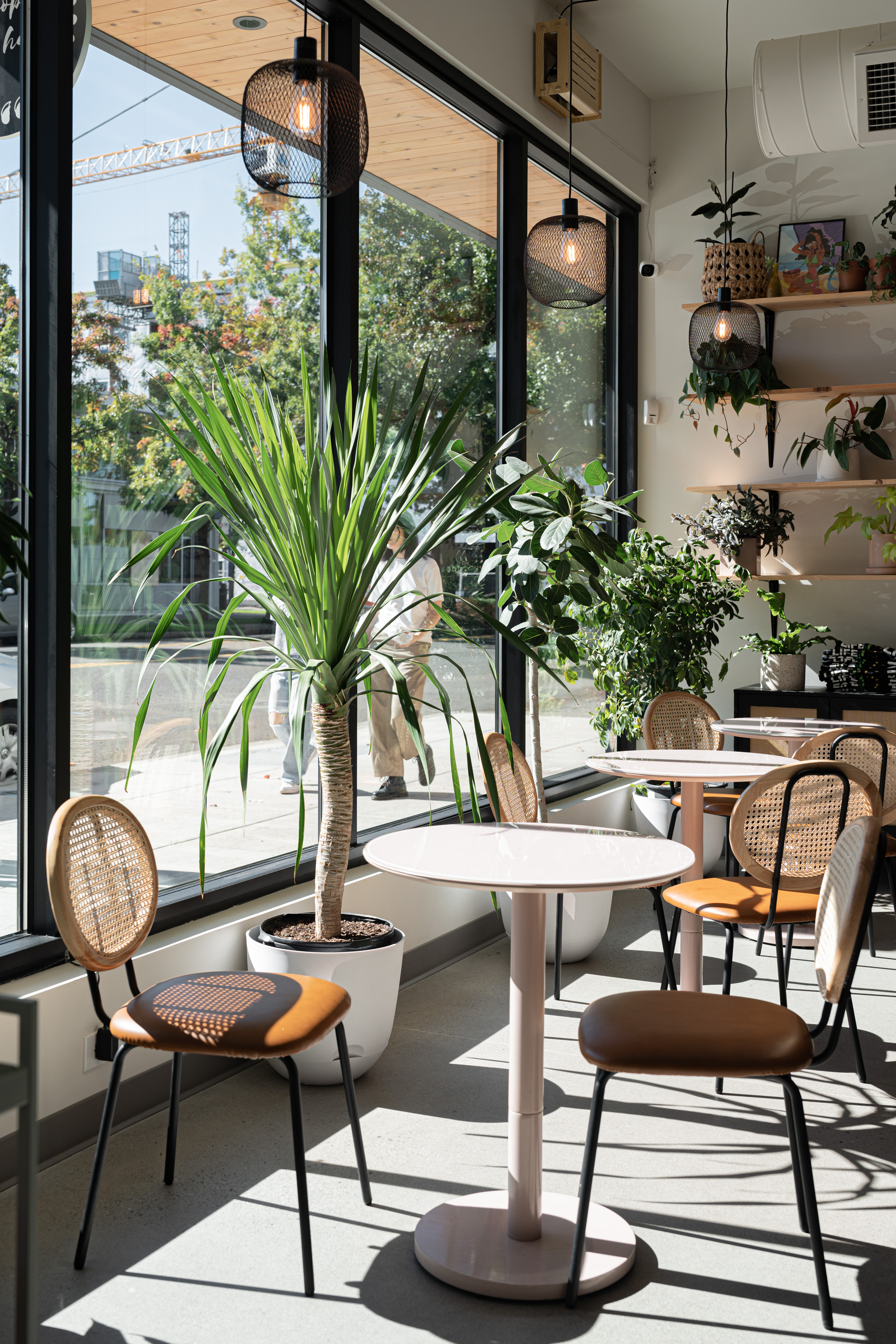 Tables next to windows in a plant-filled bakery.