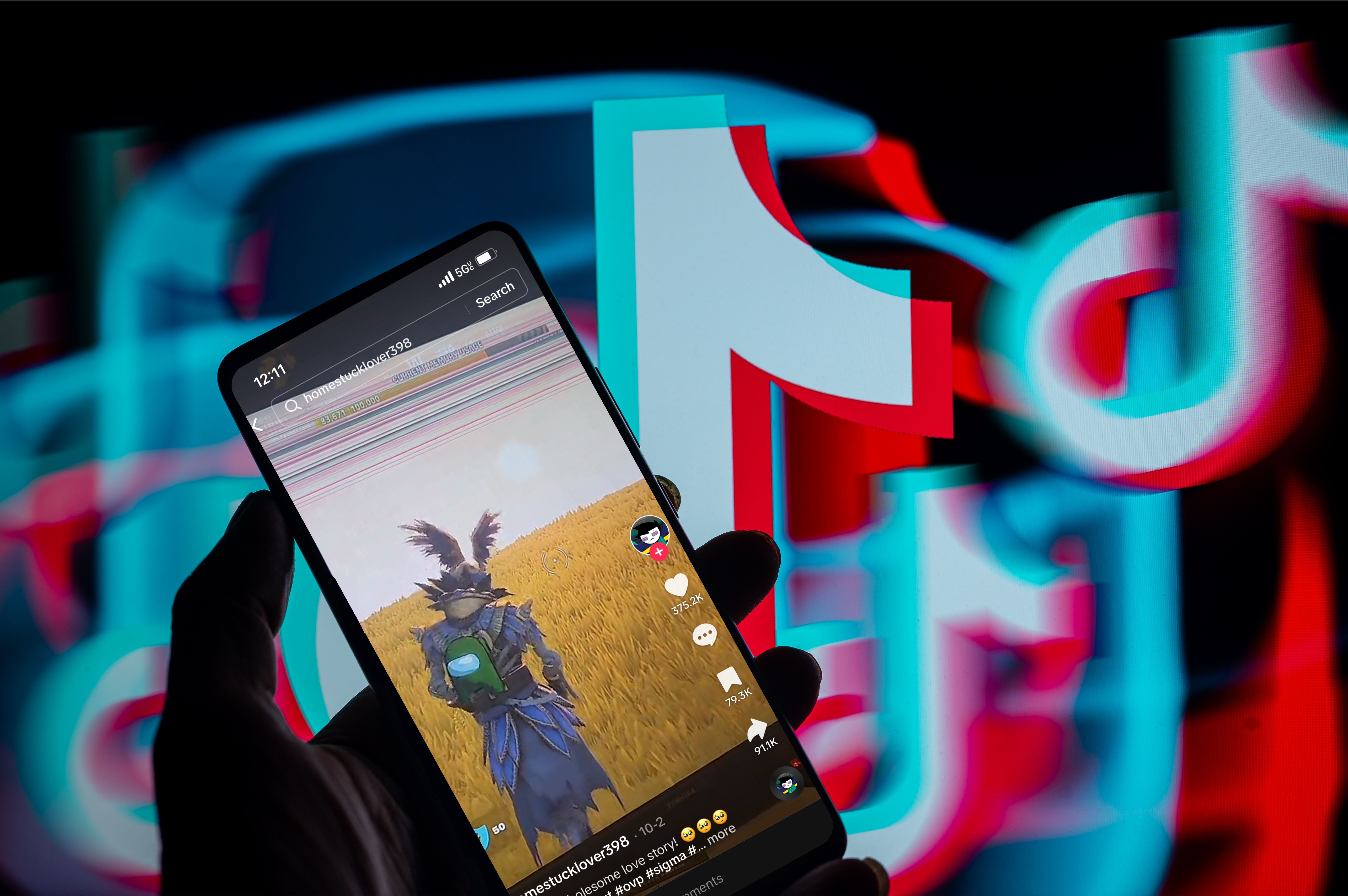A photo illustration. It shows a blurred TikTok logo and a hand holds up a phone. The phone has a screenshot of a tiktok video.