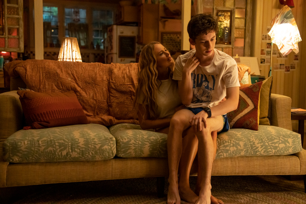 Jennifer Lawrence sits on a couch with Andrew Barth Feldman awkwardly on her lap in the movie No Hard Feelings.