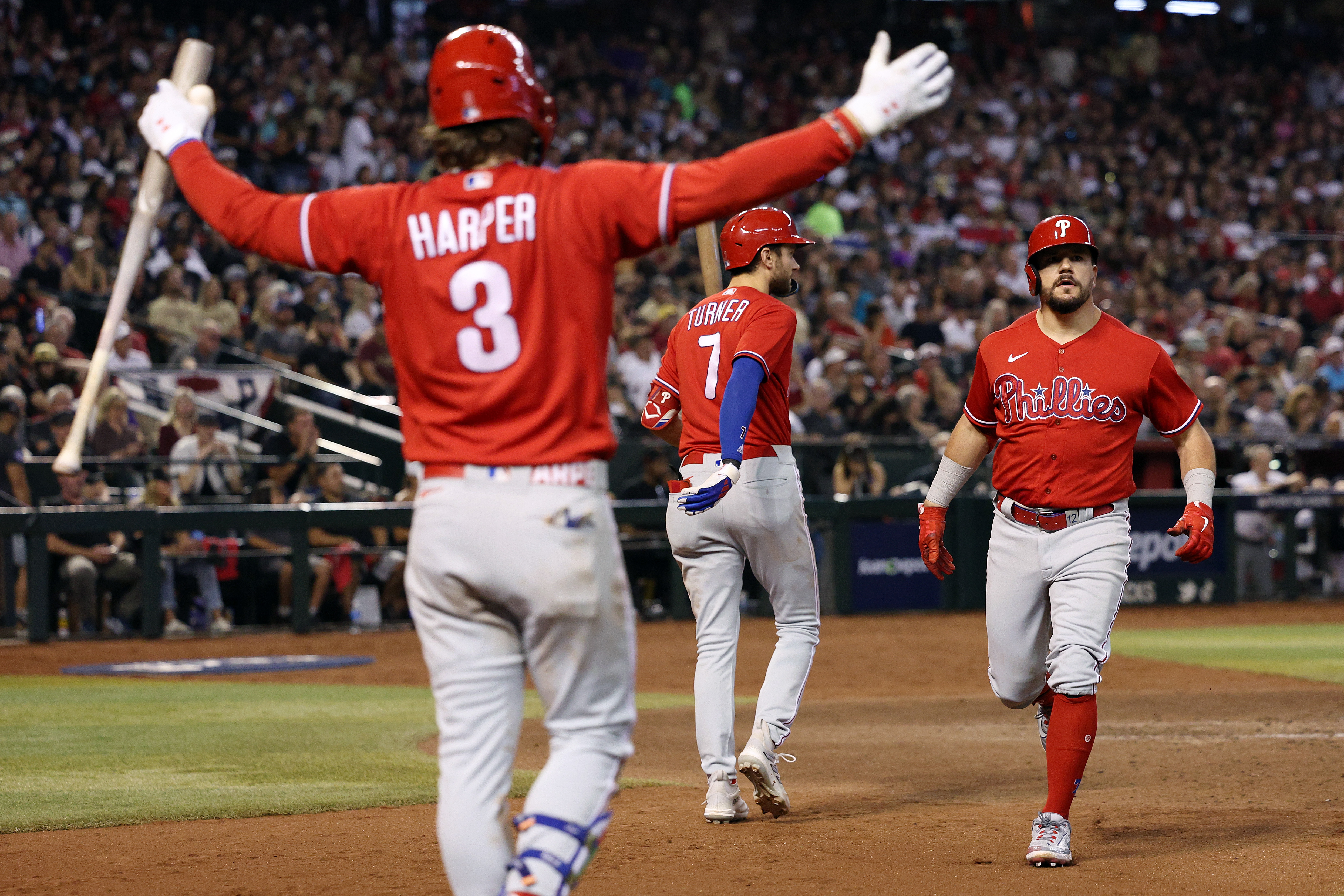 Kyle Schwarber of the Philadelphia Phillies celebrates with Trea Turner and Bryce Harper after hitting a solo home run against Zac Gallen of the Arizona Diamondbacks during the sixth inning in Game Five of the National League Championship Series at Chase Field on October 21, 2023 in Phoenix, Arizona.