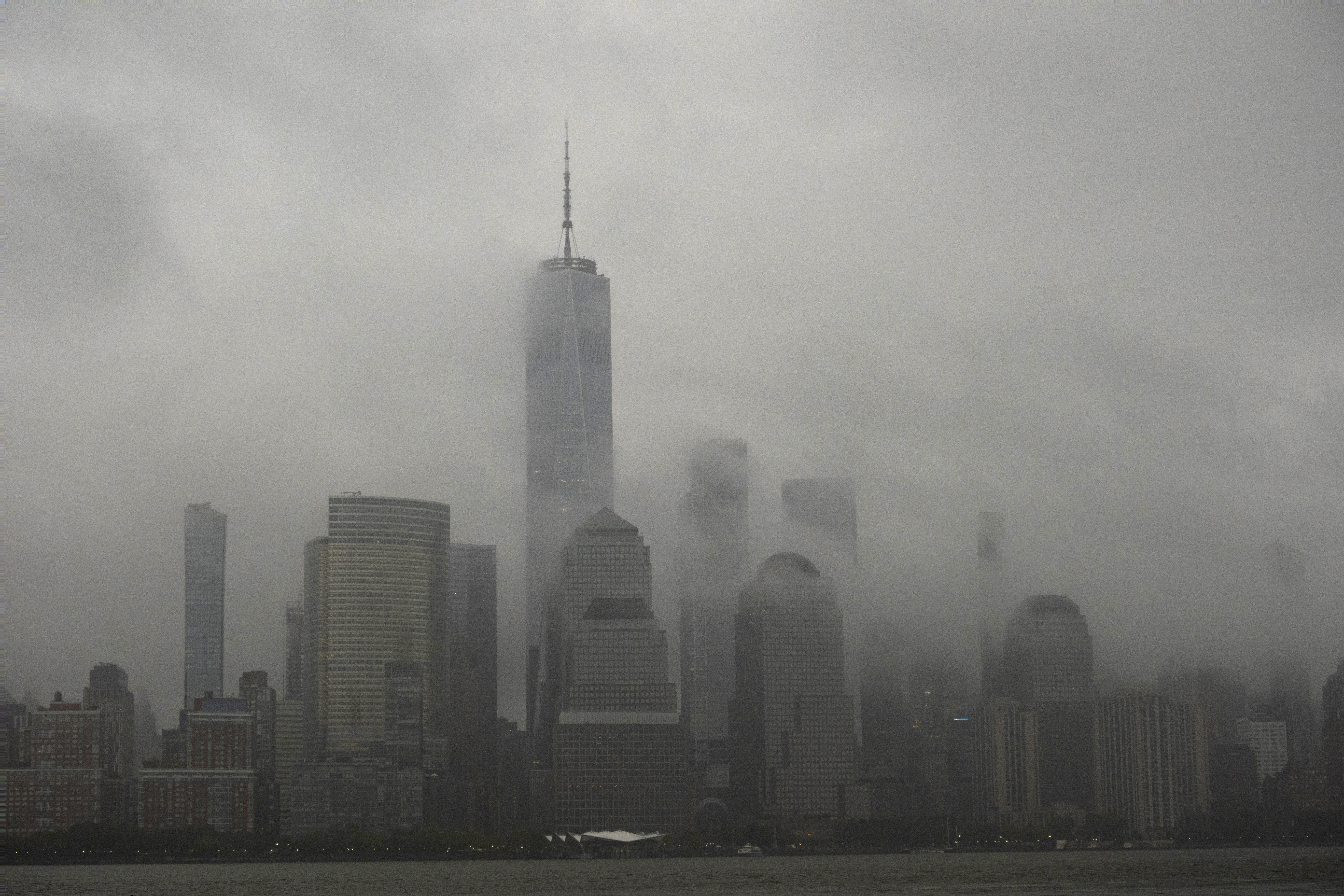 A rainstorm passes across the skyline of lower Manhattan in New York City, as seen from Jersey City, New Jersey.  The skyscrapers are shrouded in gray mist and torrents of rain.