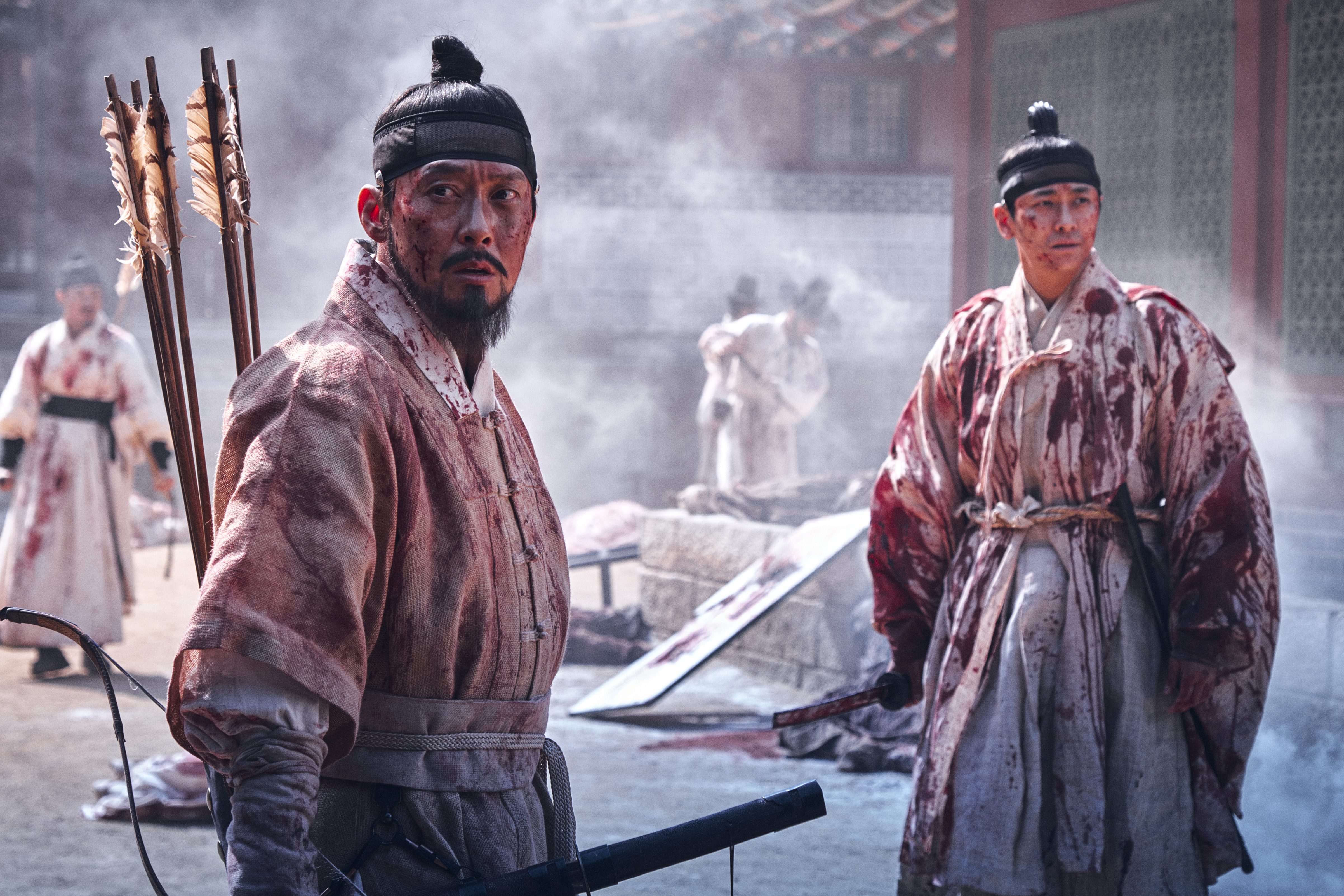 Two Korean warriors standing and surveying post-battle covered in blood, in Kingdom