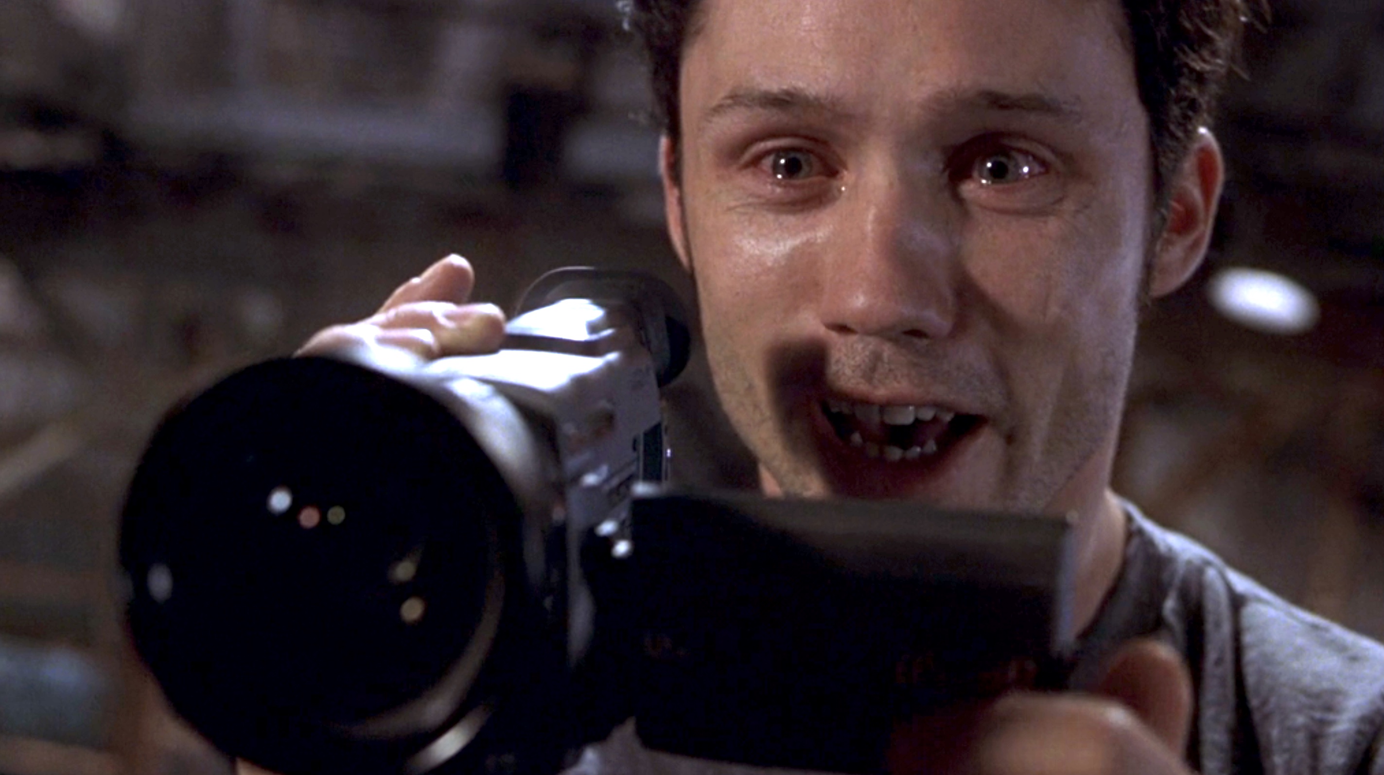 Jeff from Blair Witch 2 holding up a miniDV camera while his eyes water