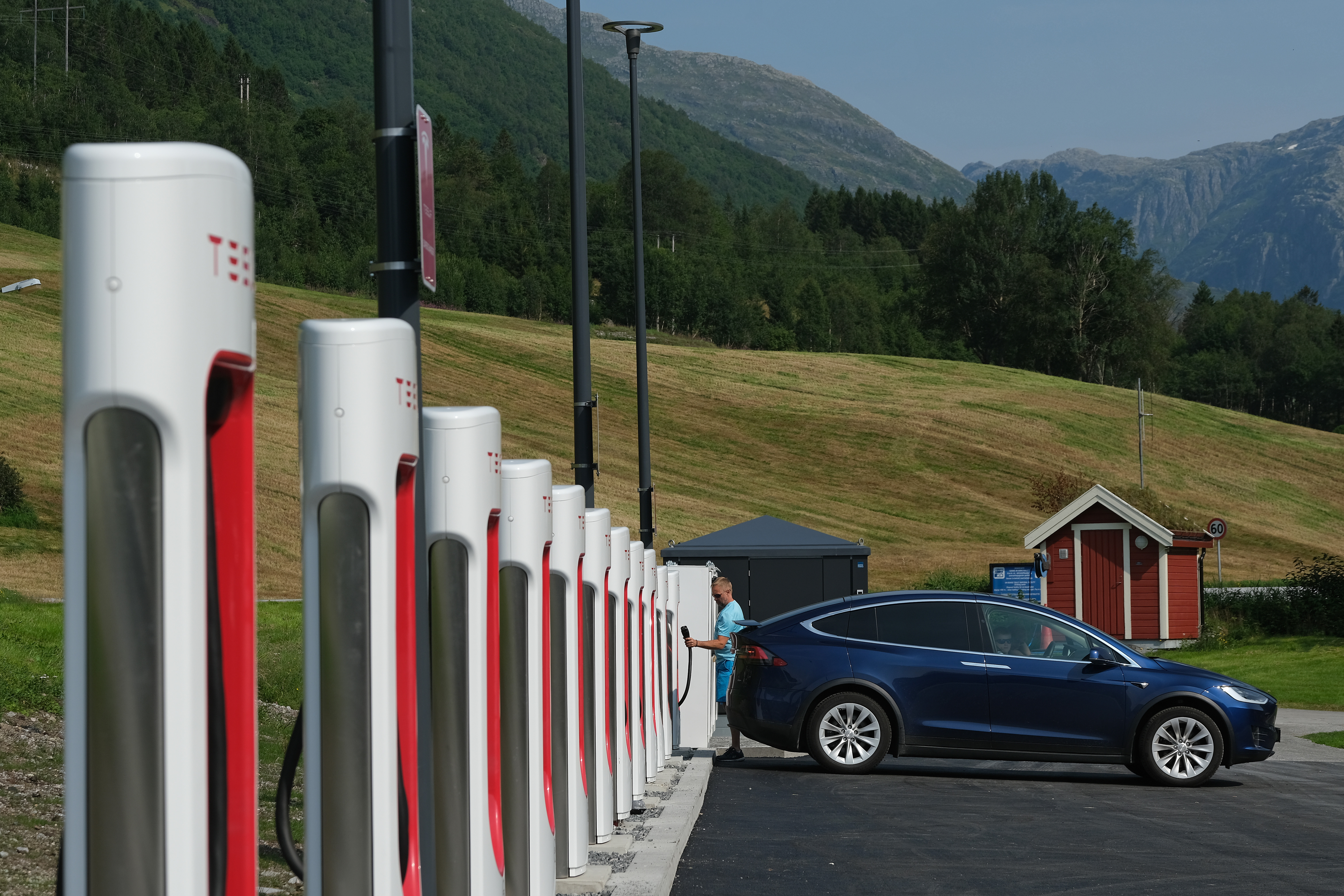 A lone Tesla is seen at a large charging station in a mountainous area.