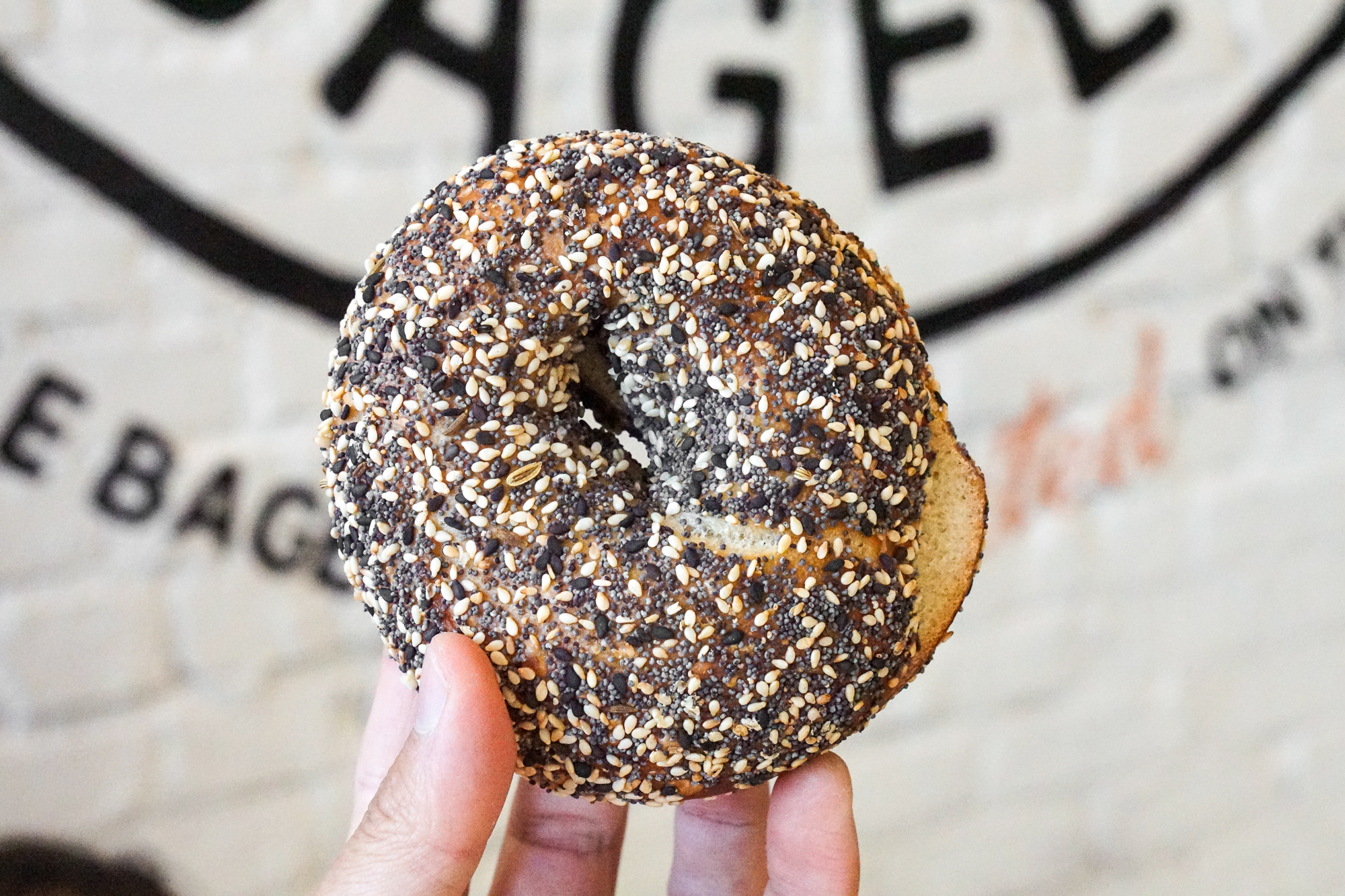 A bagel with toppings held by hand.