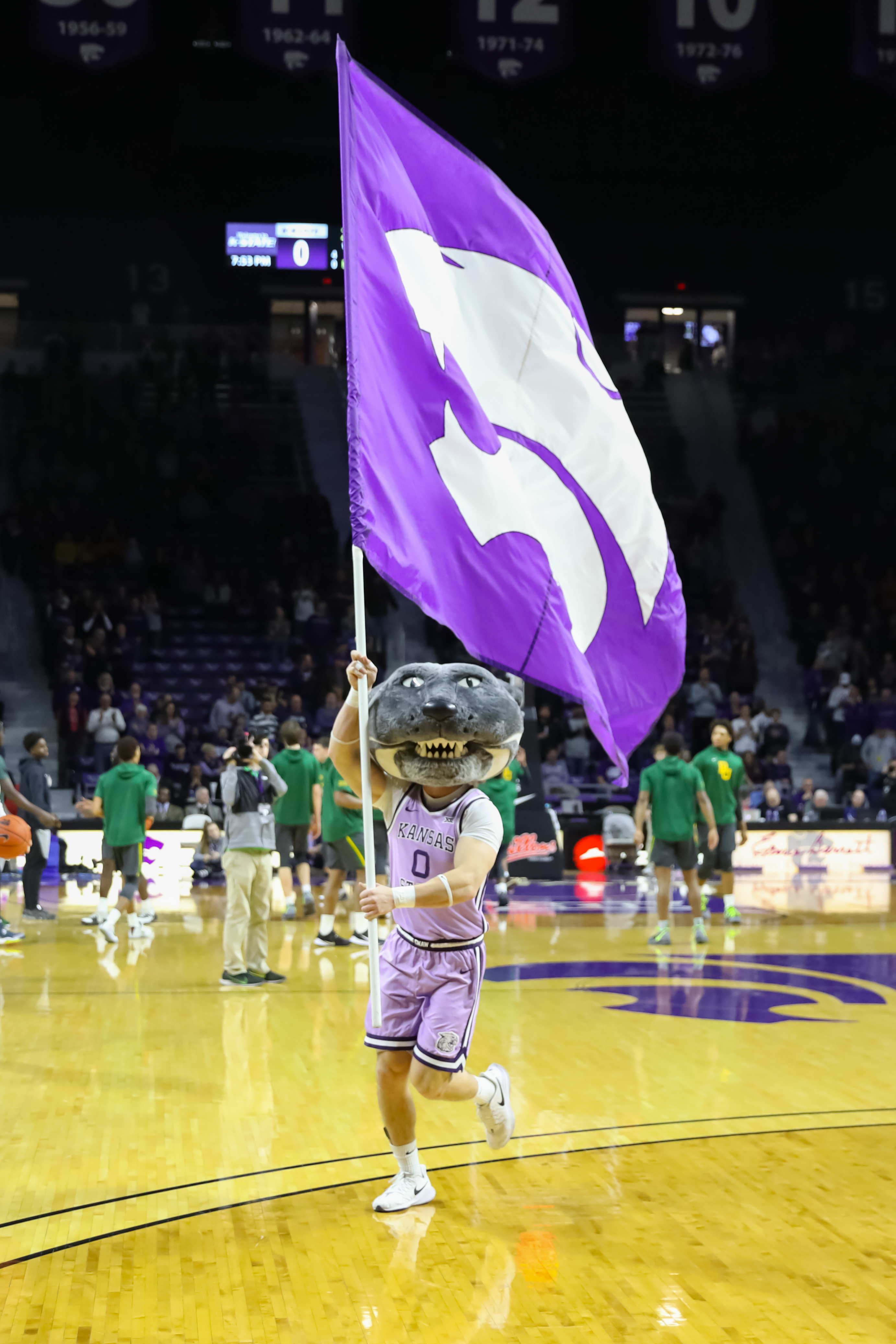 Kansas State Wildcats mascot Willie the Wildcat runs on the court with a giant flag before a Big 12 basketball game between the Baylor Bears and Kansas State Wildcats on February 3, 2020 at Bramlage Coliseum in Manhattan, KS.