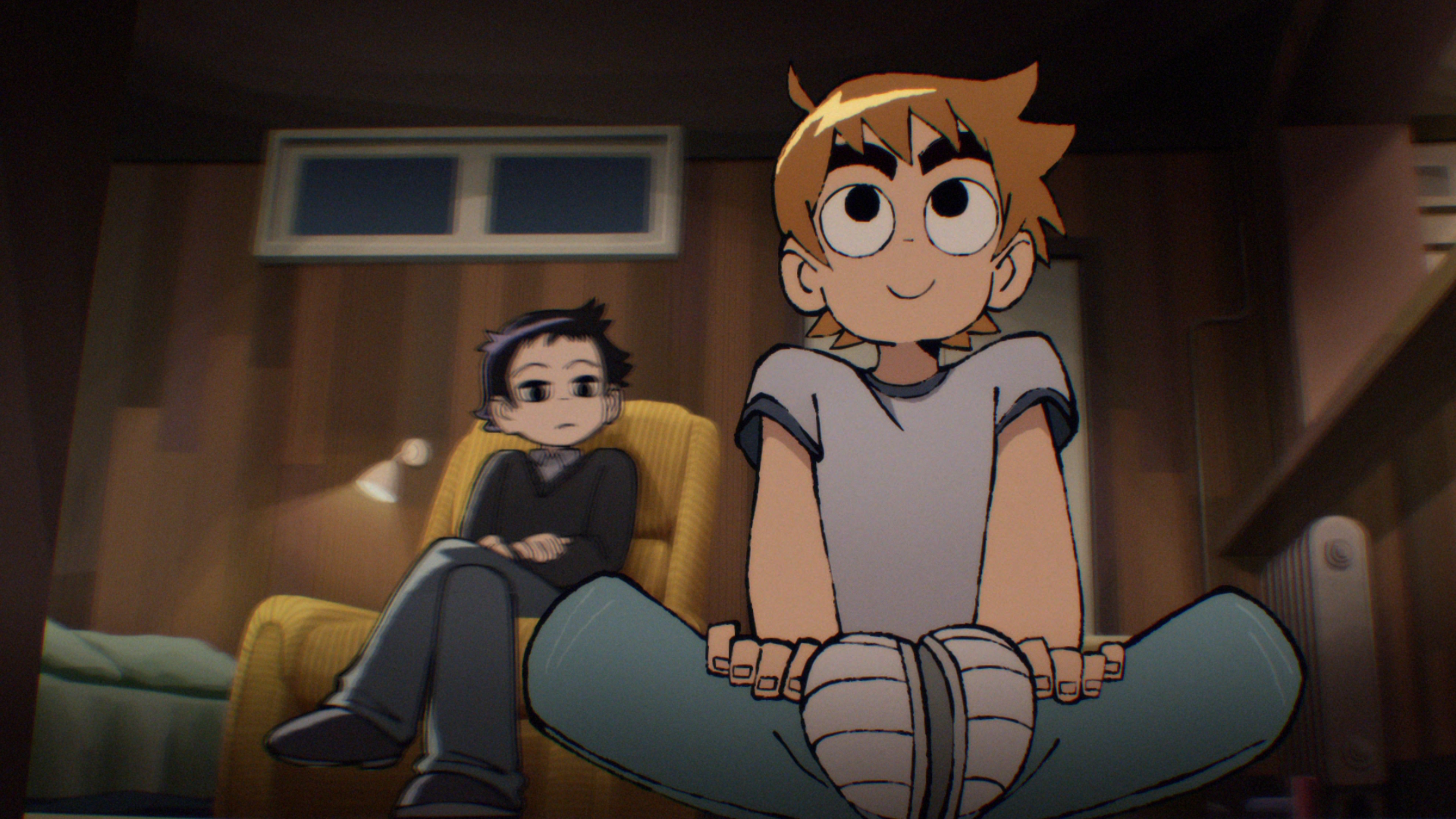 Scott Pilgrim sitting on the floor looking excited with Wallace crossing his arms in the chair behind him