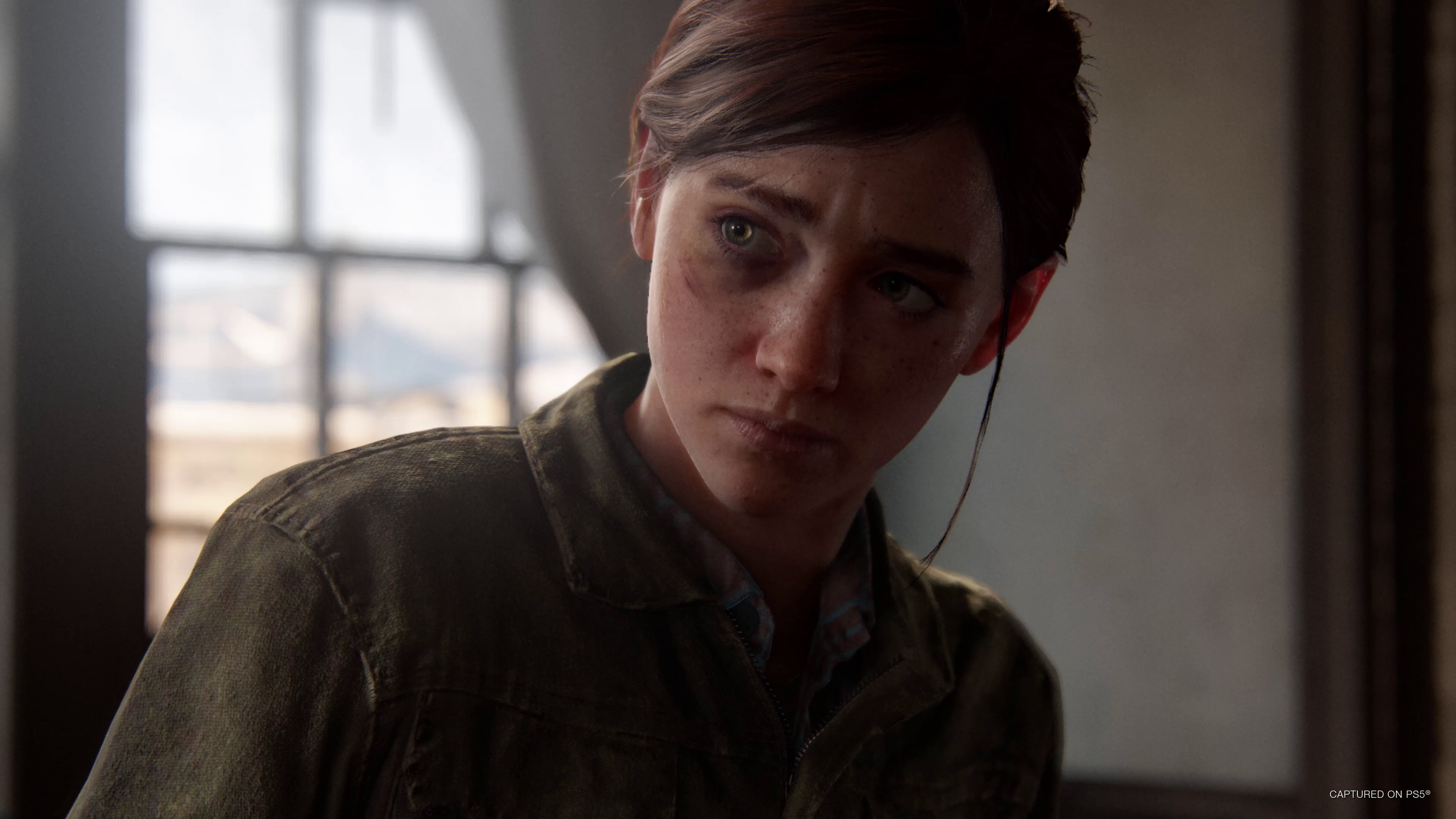 Ellie, a young woman with brown hair and a black eye, wearing an olive chambray zip-up shirt in The Last of Us Part 2 Remastered