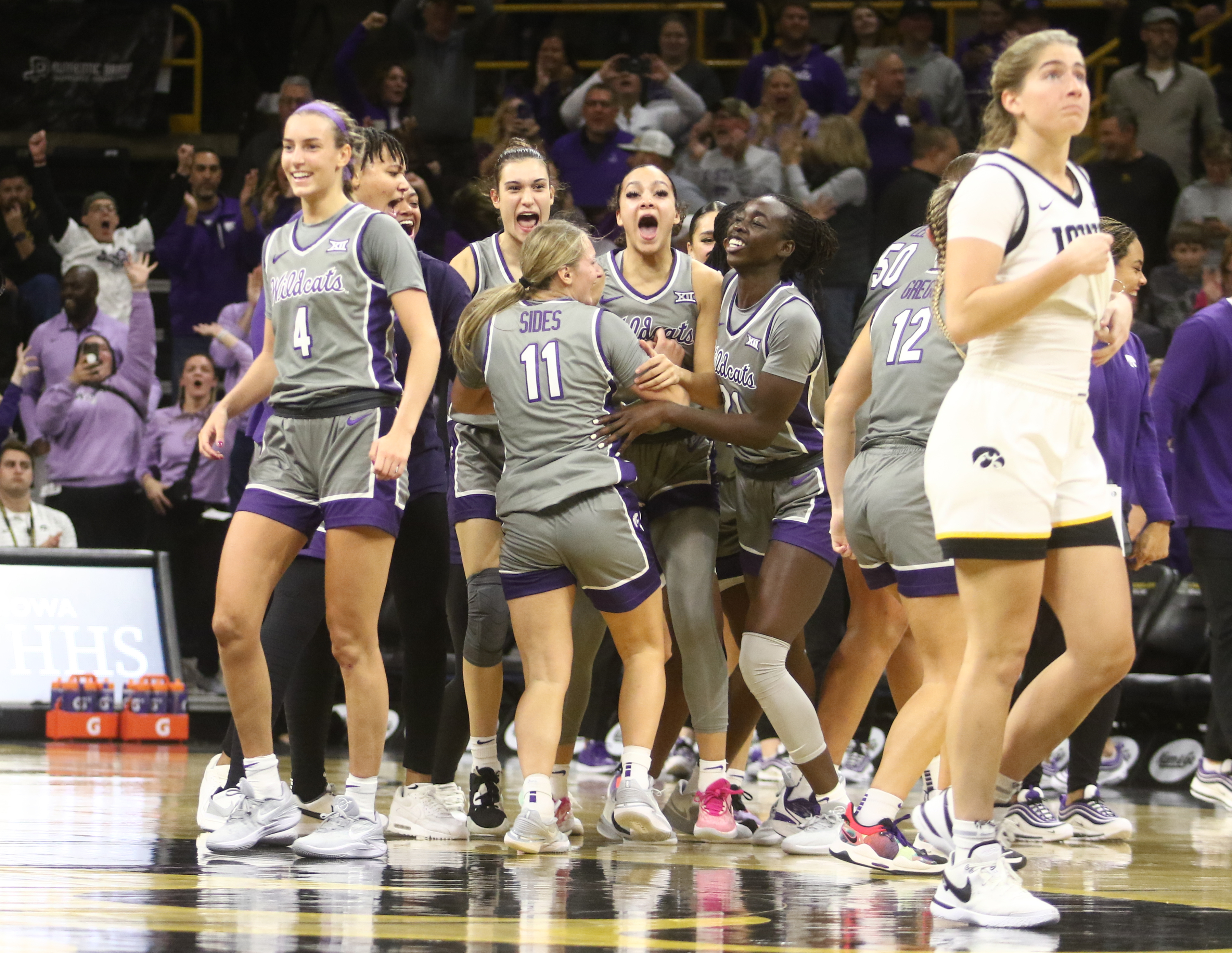 The Kansas State Wildcats celebrate the upset as guard Kate Martin #20 of the Iowa Hawkeyes walks off the court at Carver-Hawkeye Arena on November 16, 2023 in Iowa City, Iowa.