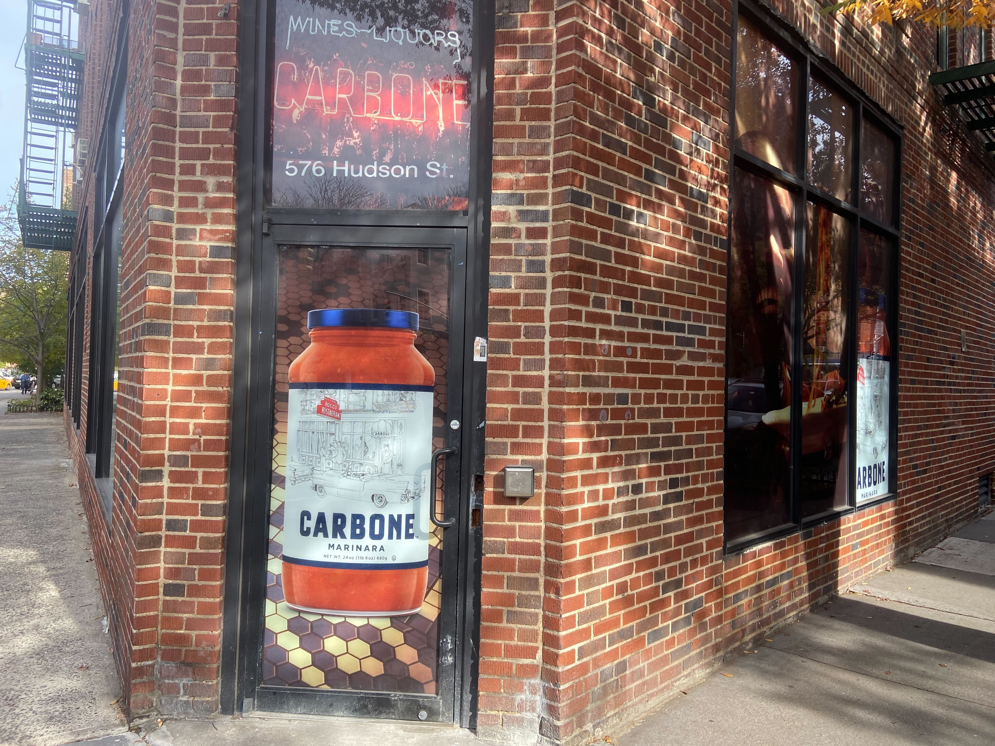 The exterior of 576 Hudson Street with signage for Carbone pasta sauce.
