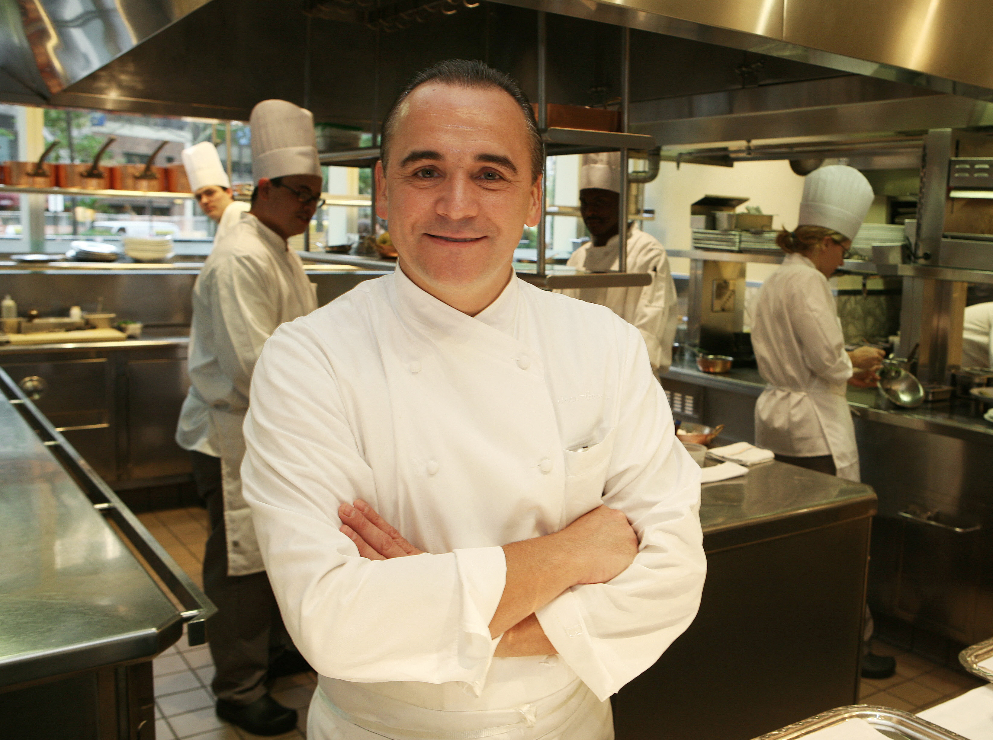 Chef Jean-Georges Vongerichten crossing his arms in front of kitchen staff at work.