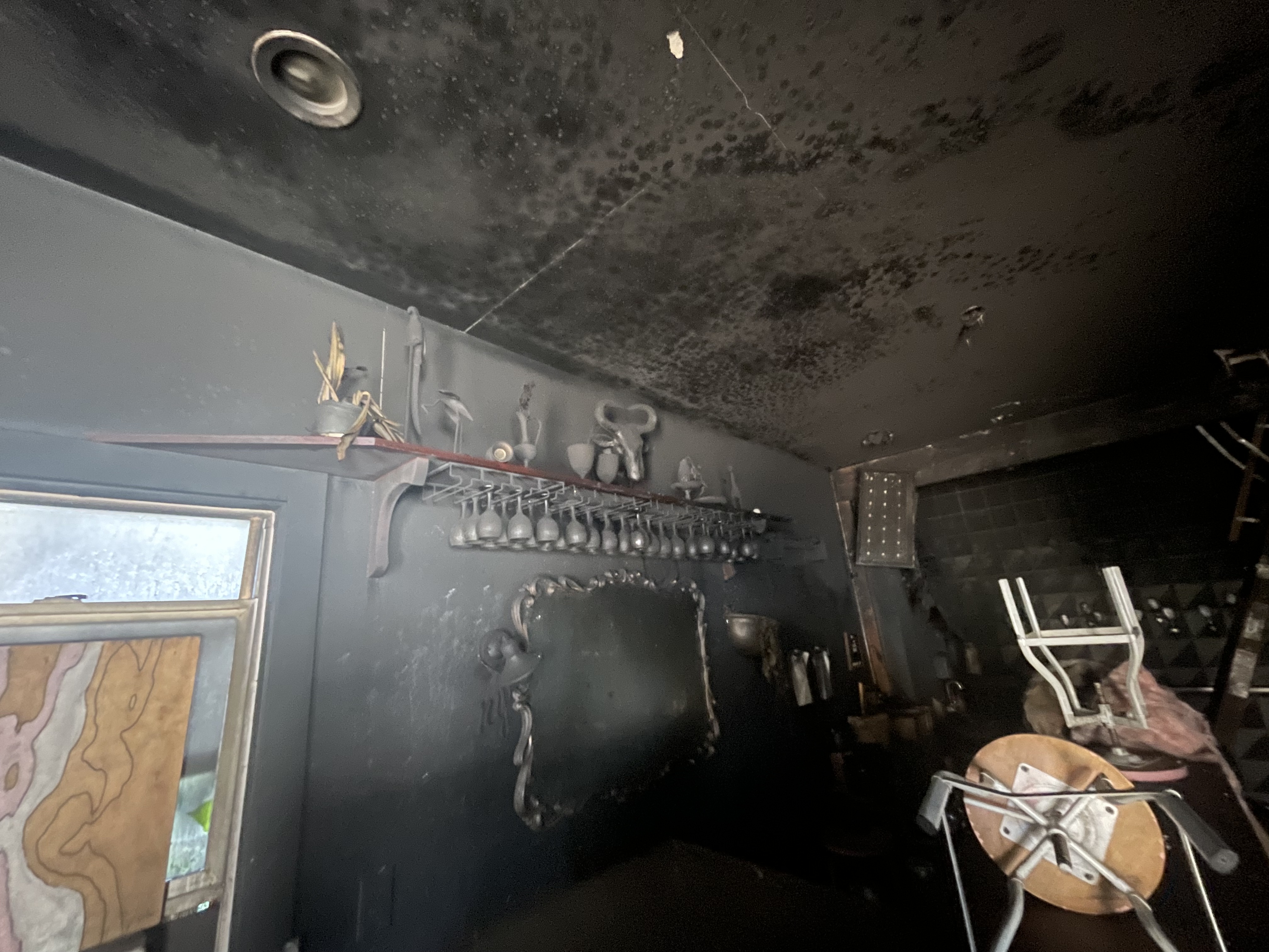 A smoke-damaged cafe with wine glasses hanging above the bar.