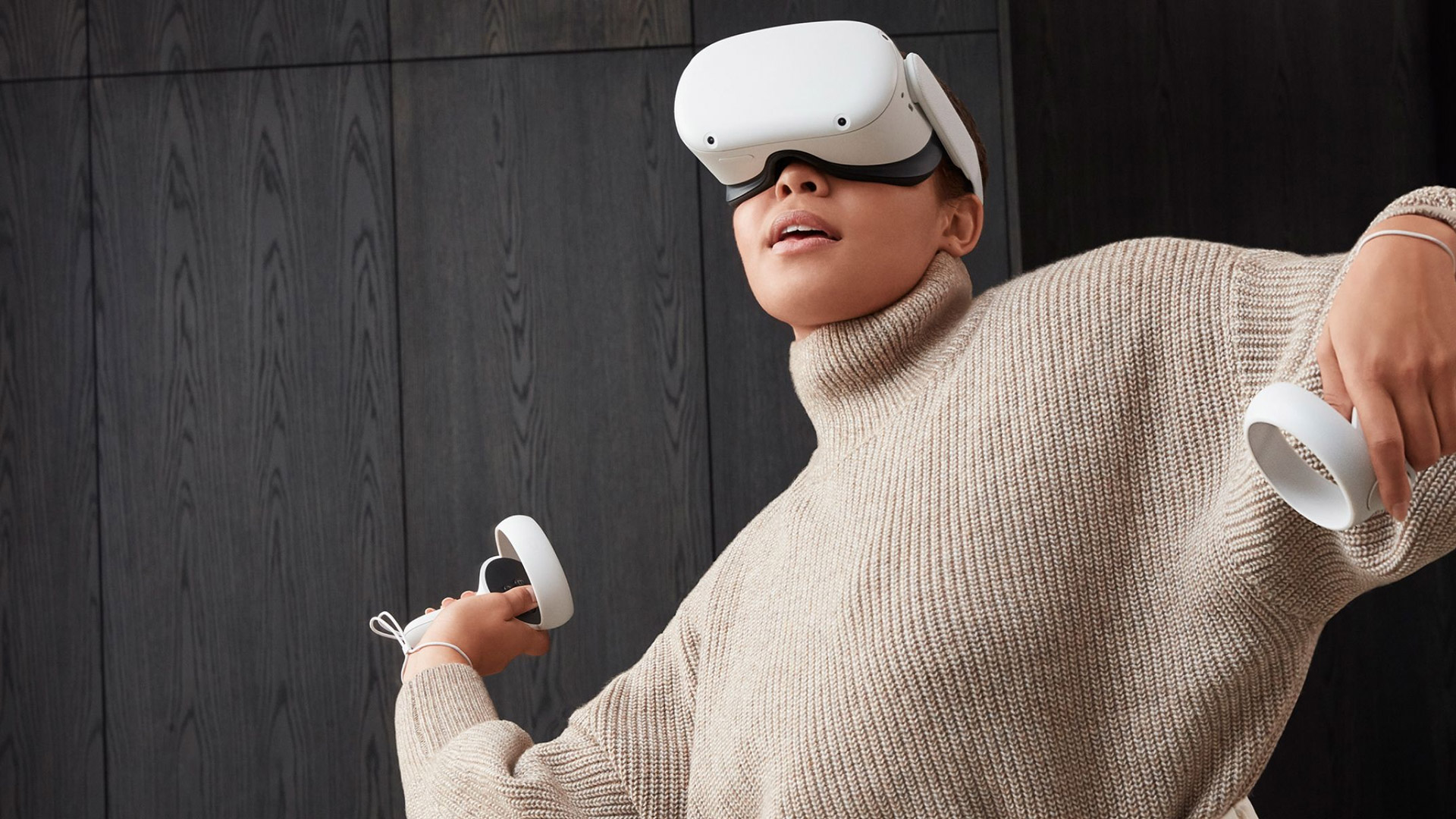 A woman wearing a turtleneck sweater plays with a Meta Quest 2 headset