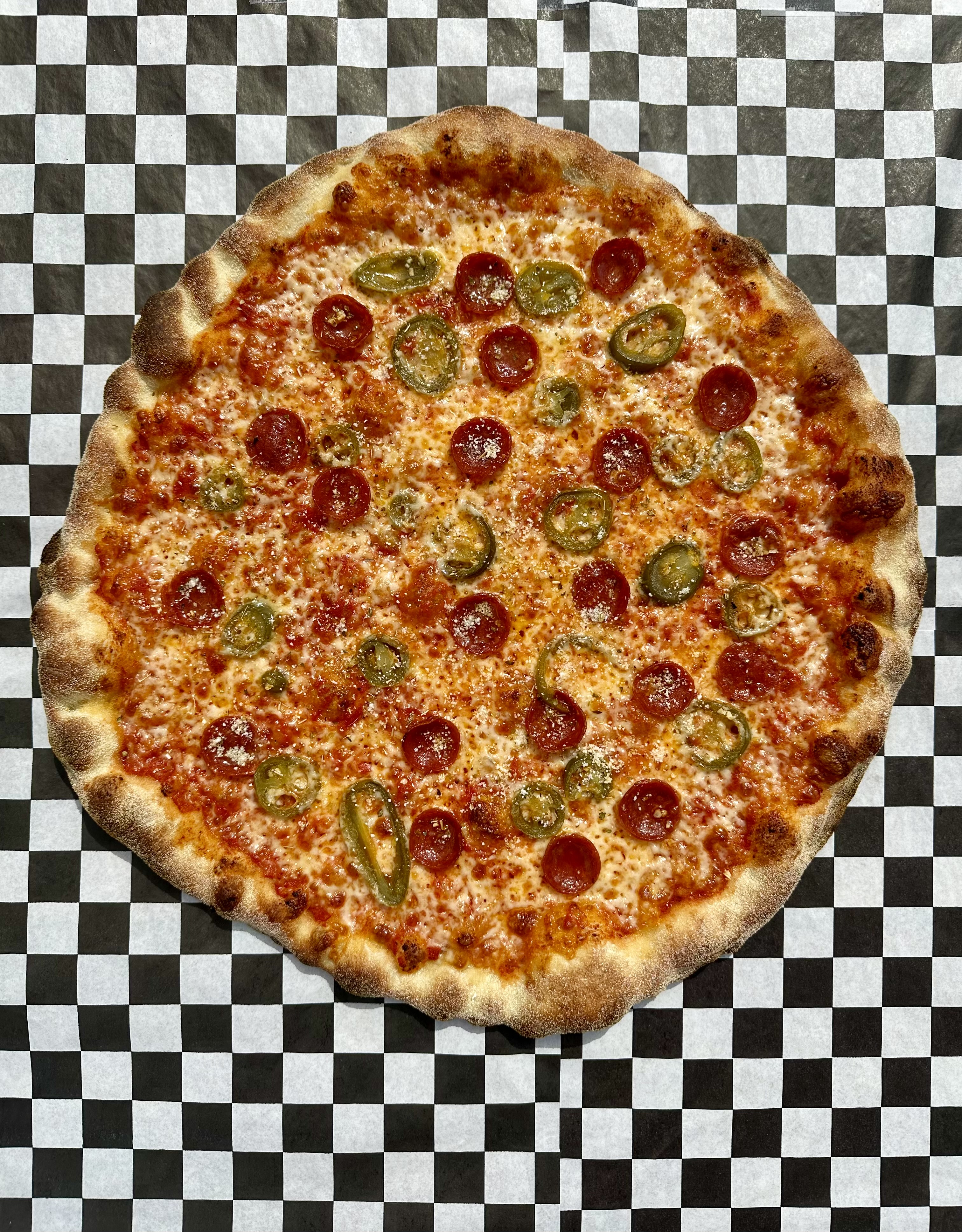 A round pizza with sliced jalapenos and pepperoni. 