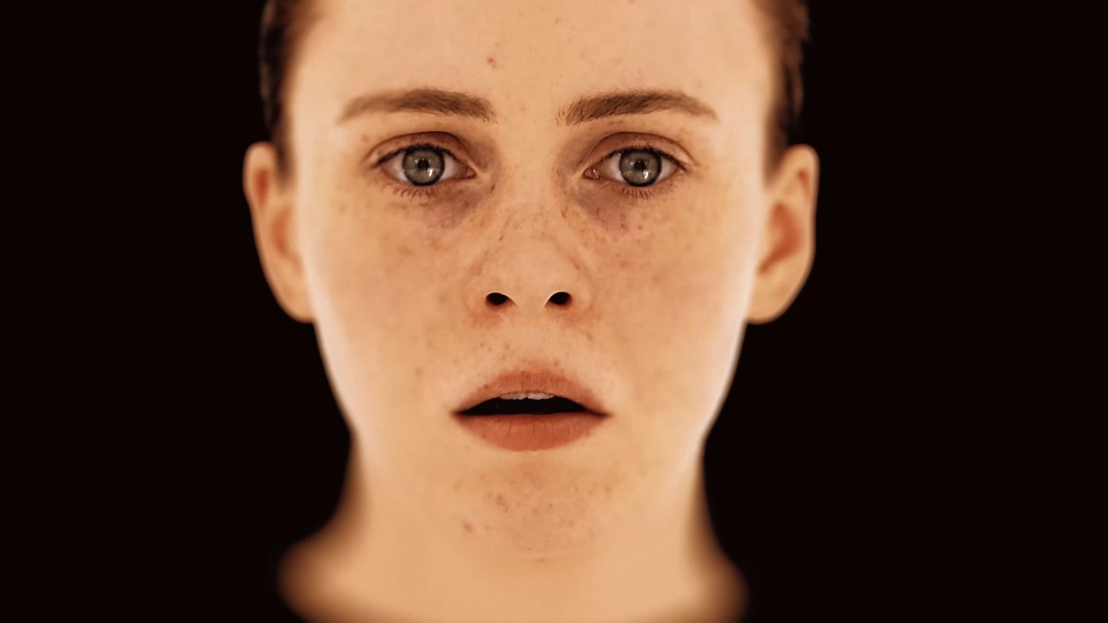 A close-up, brightly lit shot of actor Sophia Lillis looking scared, with the reflection of a room and door in her eyes, from the OD trailer