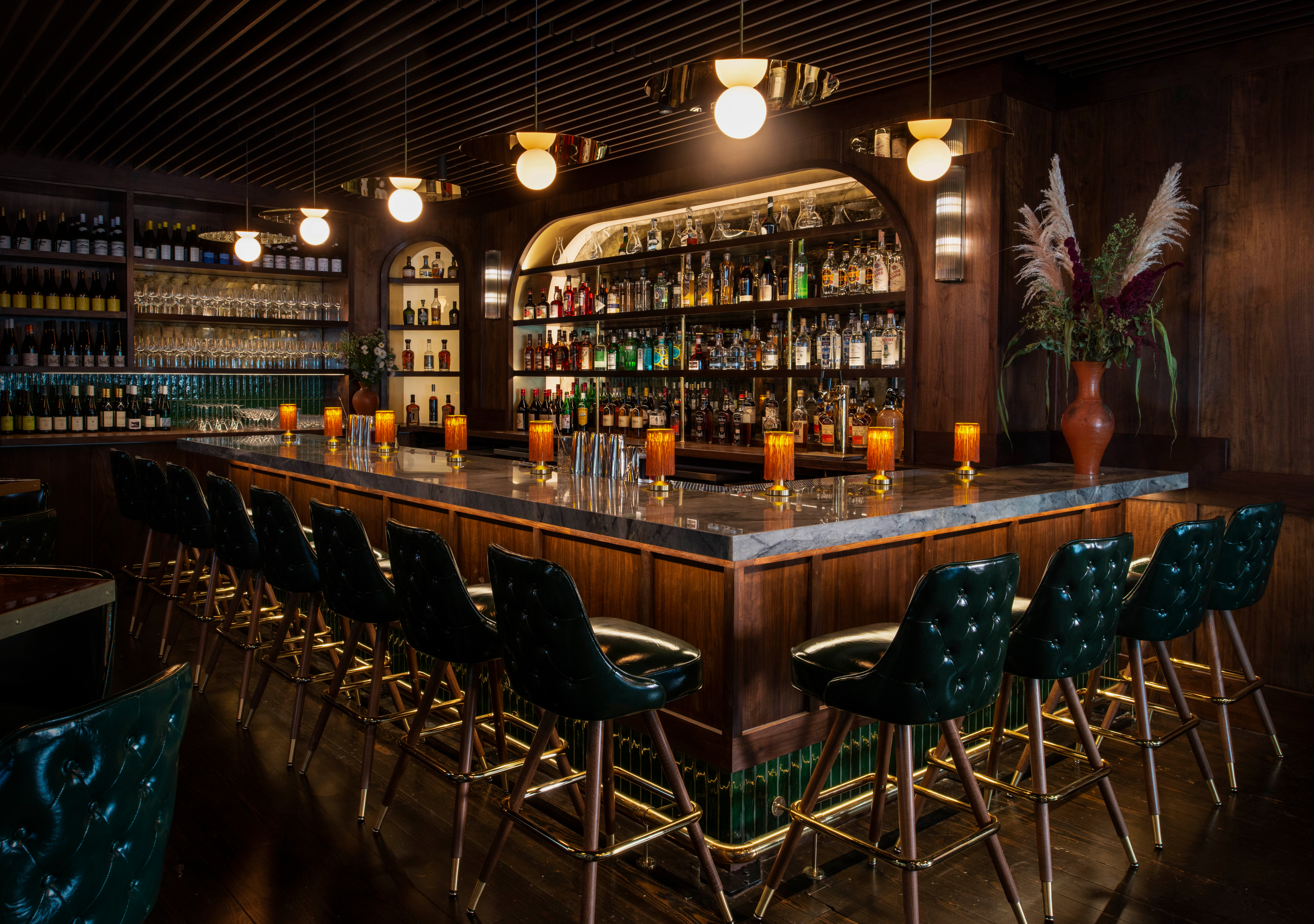 A wooden bar with black leather stools. 