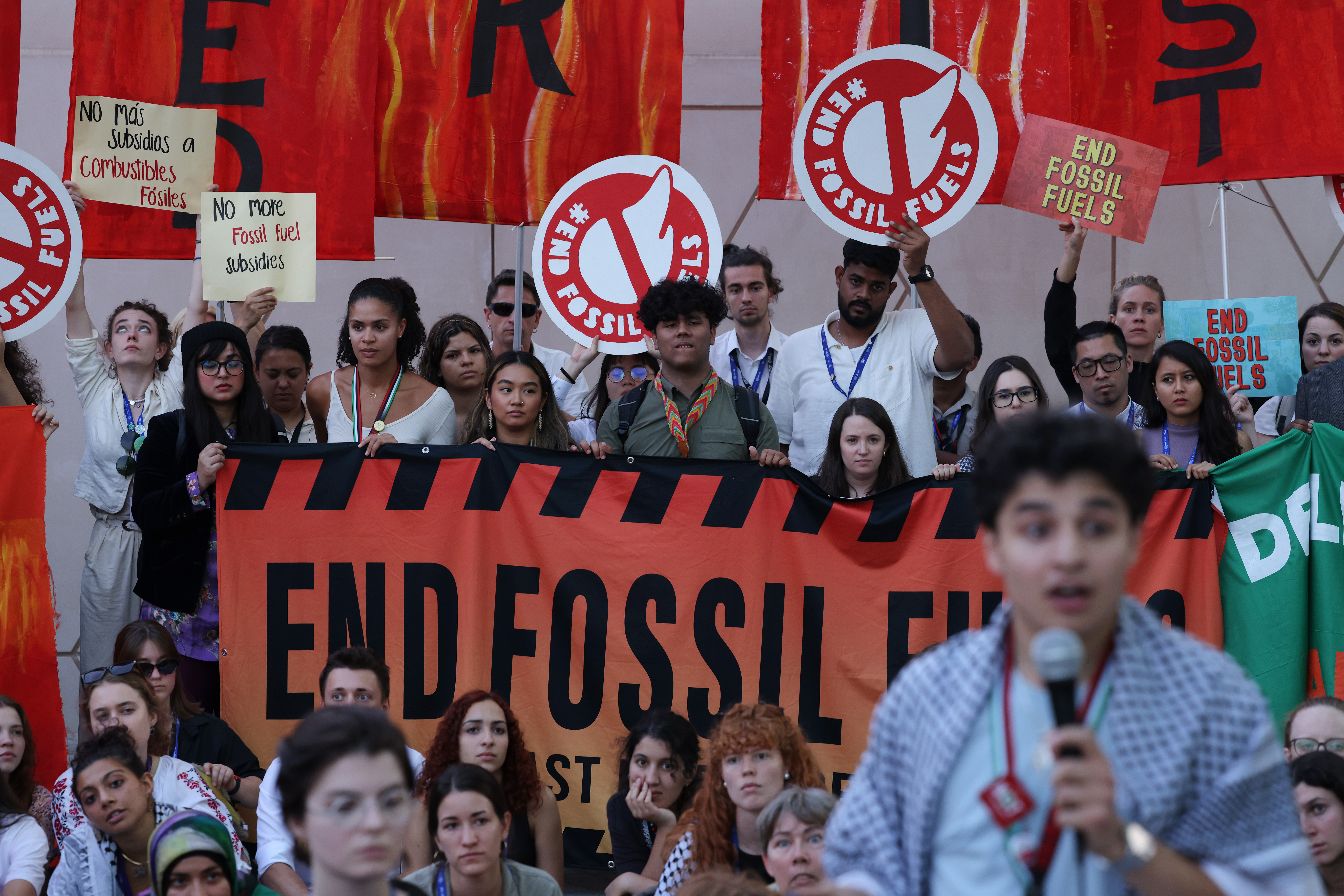 Protesters carrying circular signs and a banner that all read “End fossil fuels.” 