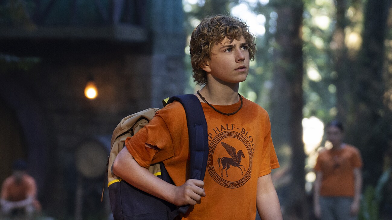 Percy Jackson (Tyler Scobell) standing with his Camp Half-blood shirt on