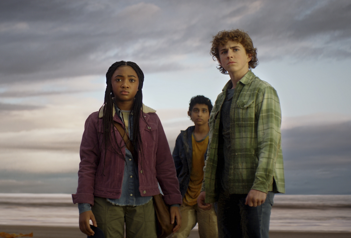 Percy (Walker Scobell), Annabeth (Leah Sava Jeffries), and Grover (Aryan Simhadri) standing on a beach